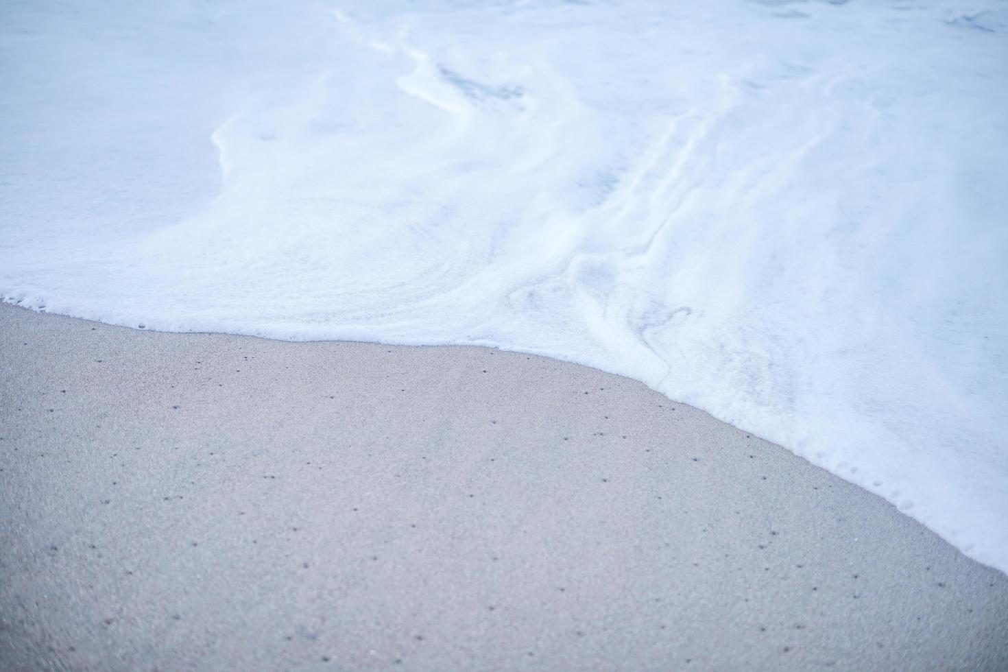 de schuimgolf op het zandstrand. zachte golven in de kustlijn die rustig en plezierig aanvoelen om te ontspannen. foto