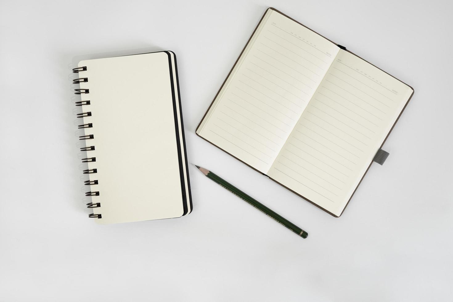wit bureau met schetsboek en potlood erop. een notebookmodel op het bureau als indeling van de werkruimte. office-object geïsoleerd op een witte achtergrond. foto