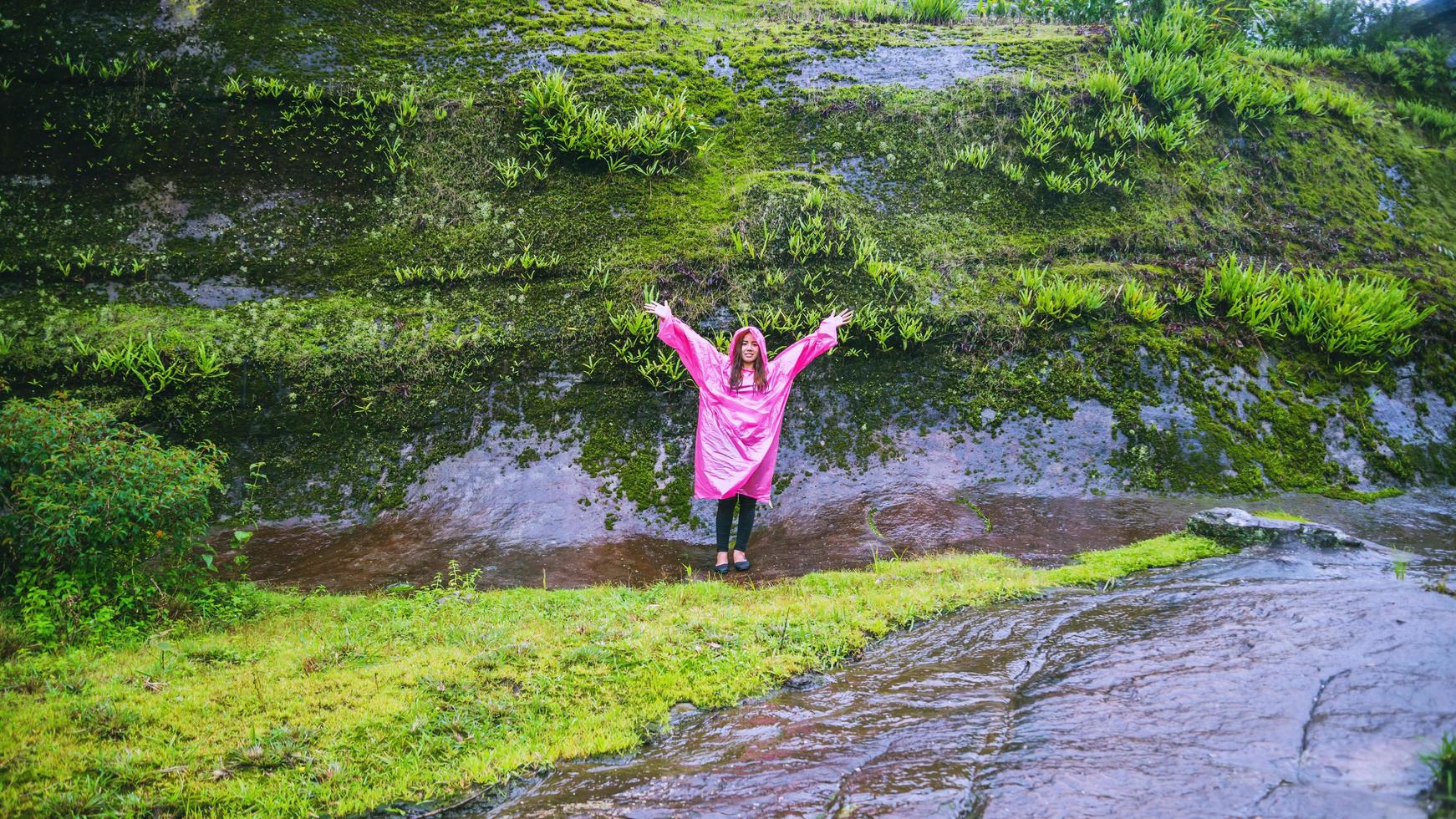 toerist met roze regenjas wandelen reizen avontuur natuur in het regenwoud. reizen natuur, reizen ontspannen, reizen thailand, regenseizoen. foto