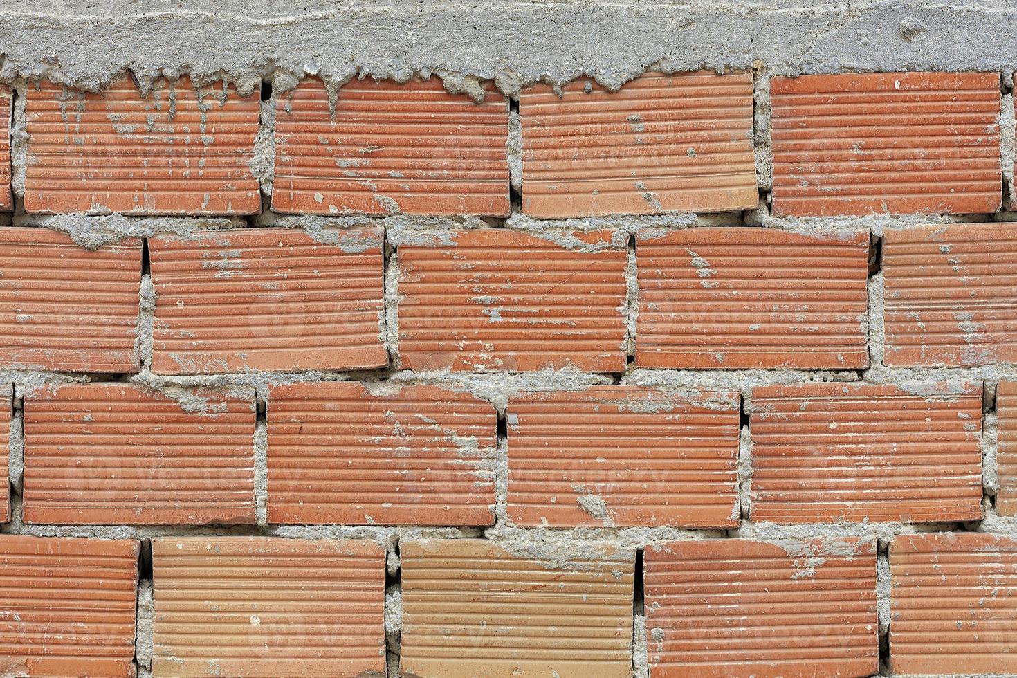 de uitgesproken textuur van corpulente baksteen op de muur met een cementnaad met cementhoed. foto