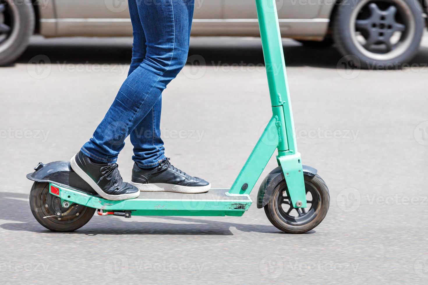 een modern concept voor mobiel elektrisch vervoer een persoon rijdt op een elektrische scooter langs de rijbaan van een stadsstraat. foto