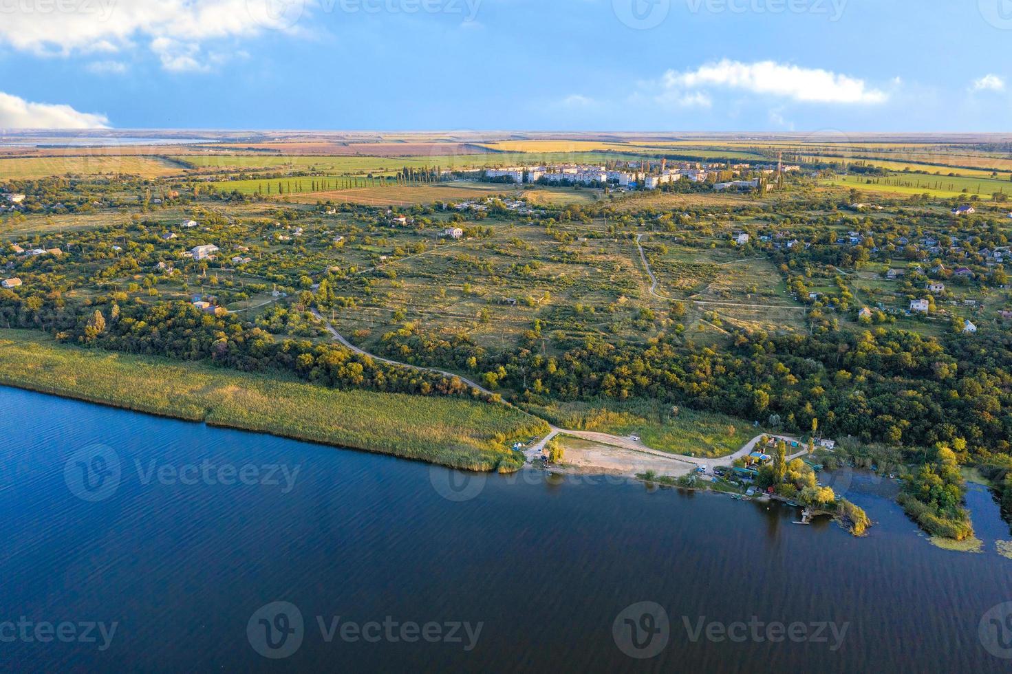 luchtfotografie, de oever van de rivier tegen de achtergrond van de zonnestralen van de zonsondergang, steppebomen en een werkend dorp op de achtergrond. foto