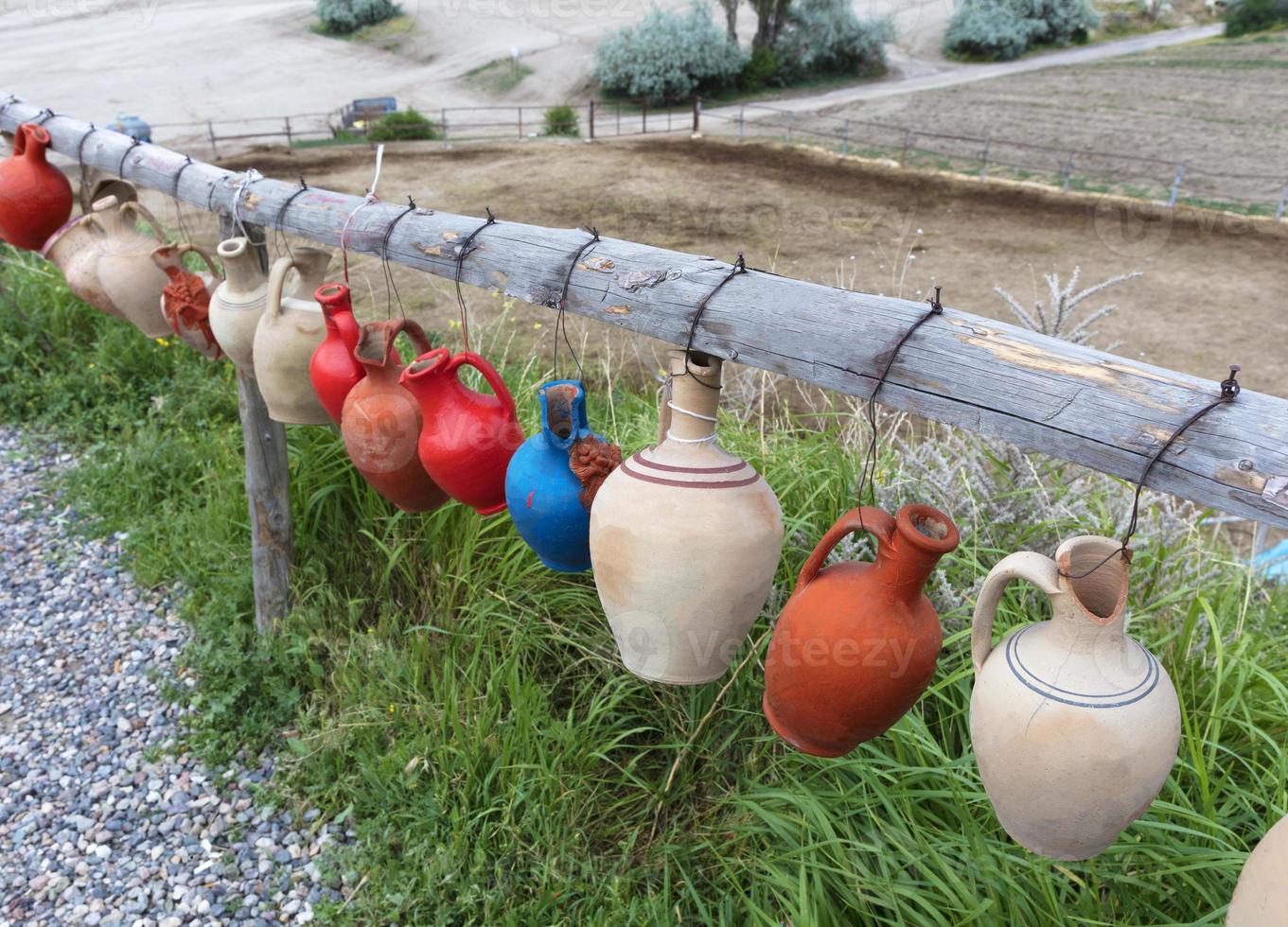 de veelkleurige kleipotten met verlangens hangen vastgebonden aan een houten dwarsbalk in Cappadocië. foto