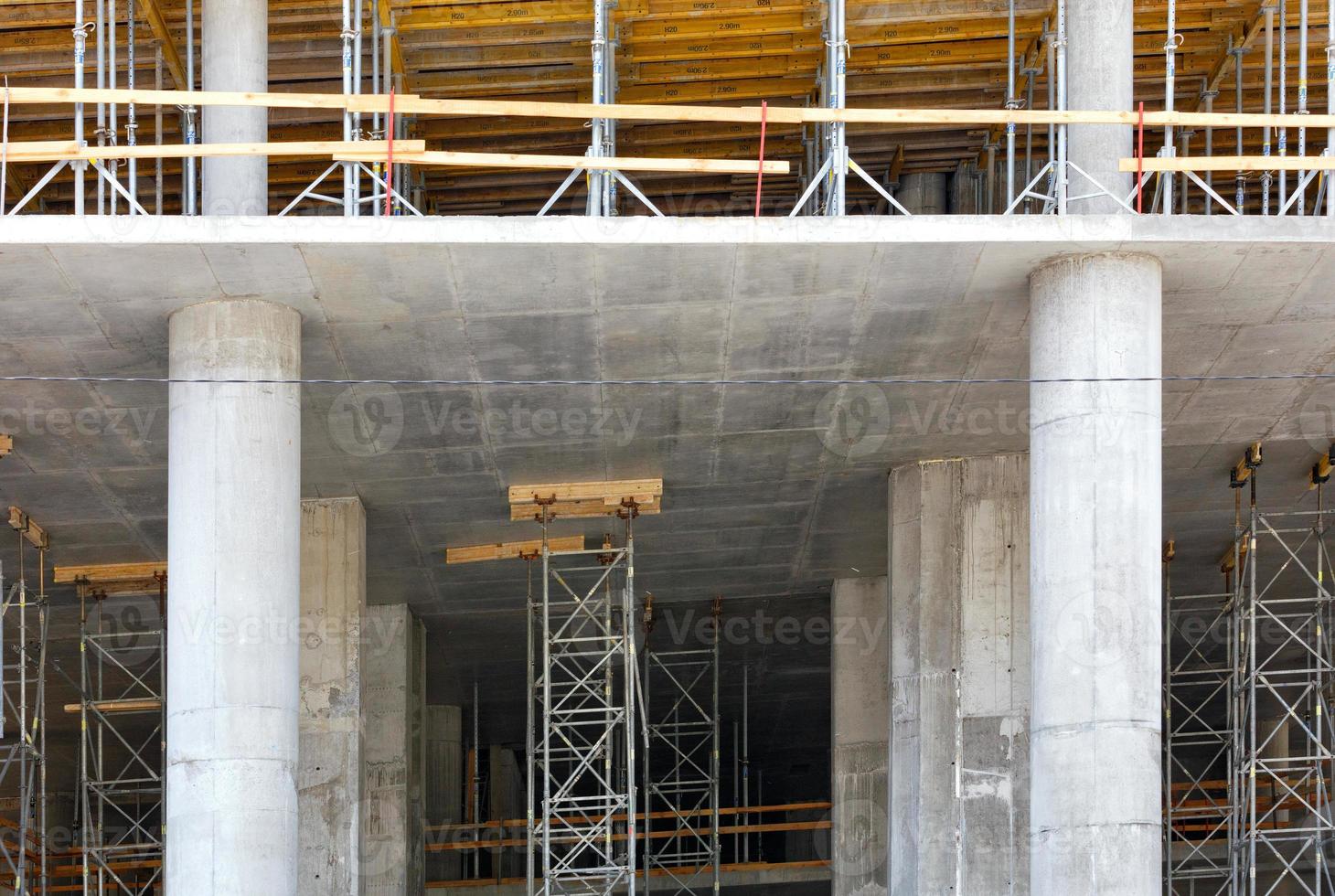 het concept van de constructie van nieuwe gebouwen met behulp van een monolithische framemethode, betonnen kolommen met steigers, bekisting en metalen steunen. foto