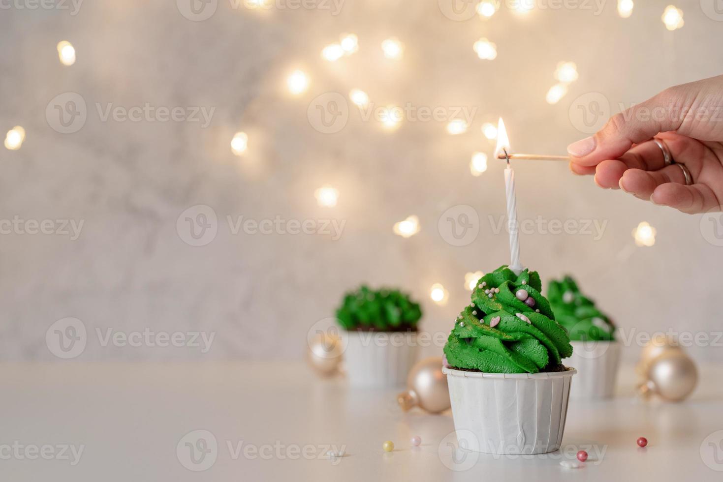 kerstboomvormige cupcakes, omringd met feestelijke versieringen en lichtjes op de achtergrond foto