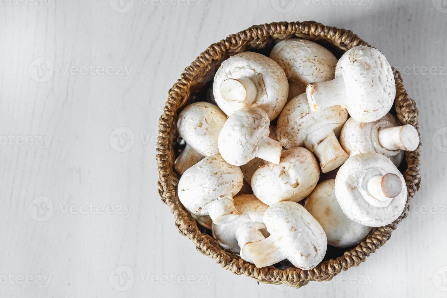 champignons champignons in een ronde rieten mand op een witte houten tafel foto