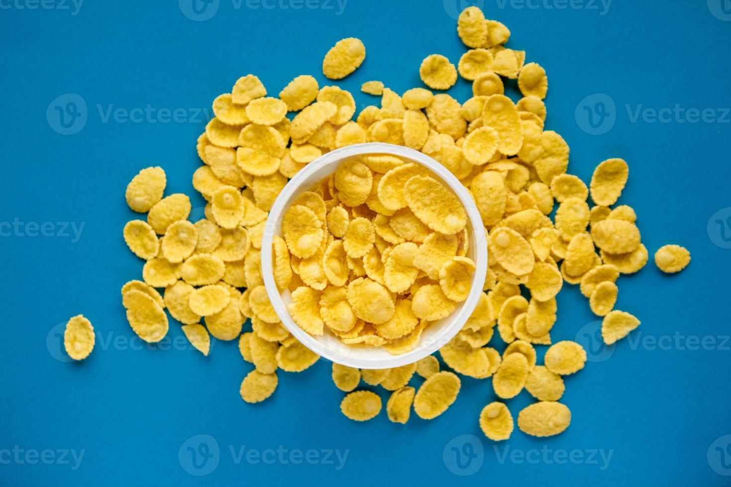 cornflakes in witte kom op blauwe achtergrond foto