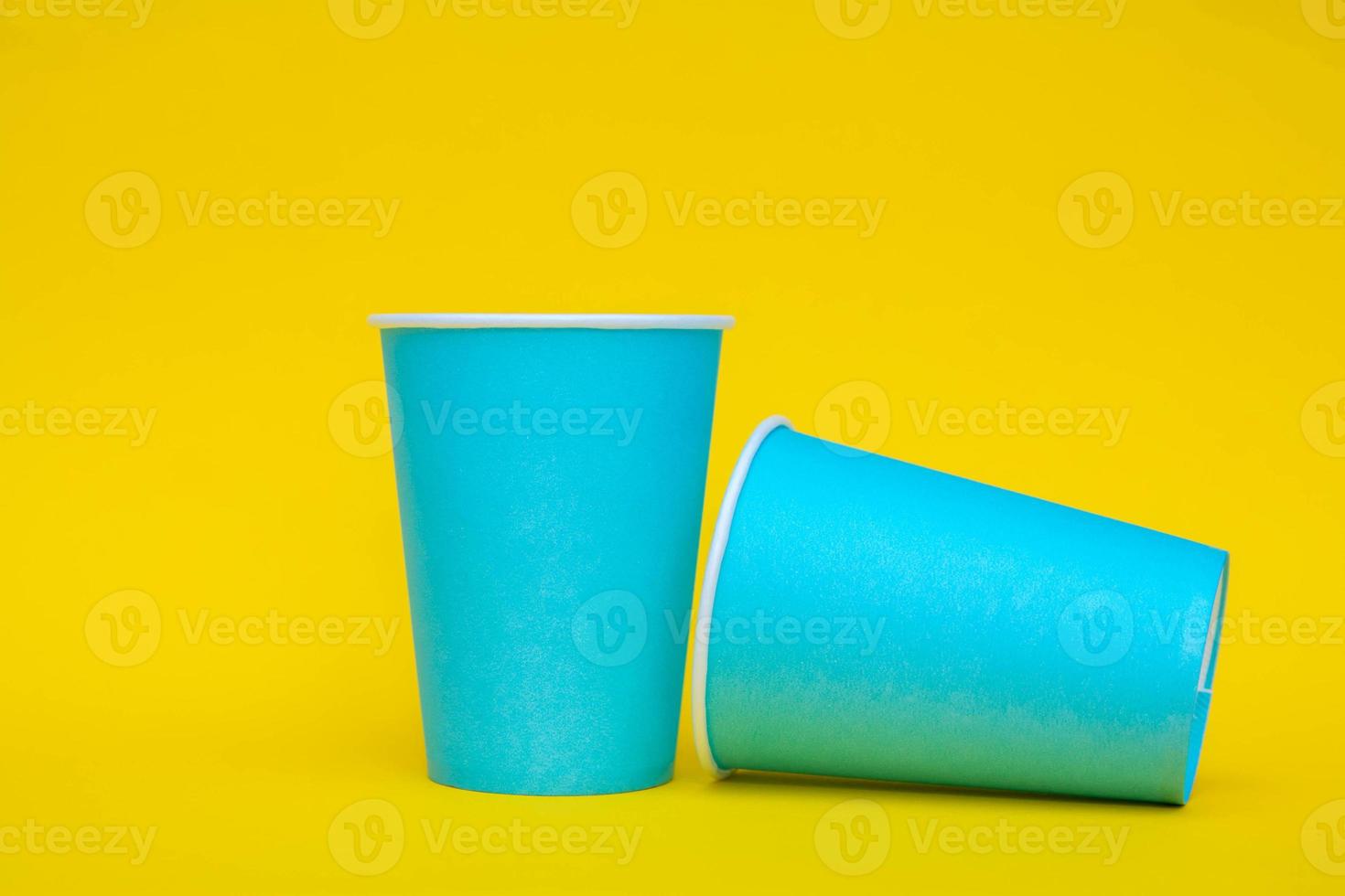 twee blauwe papieren bekers op gele achtergrond foto