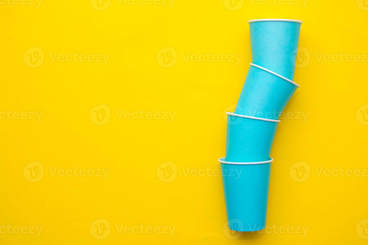 blauwe papieren wegwerpbekers op gele achtergrond foto