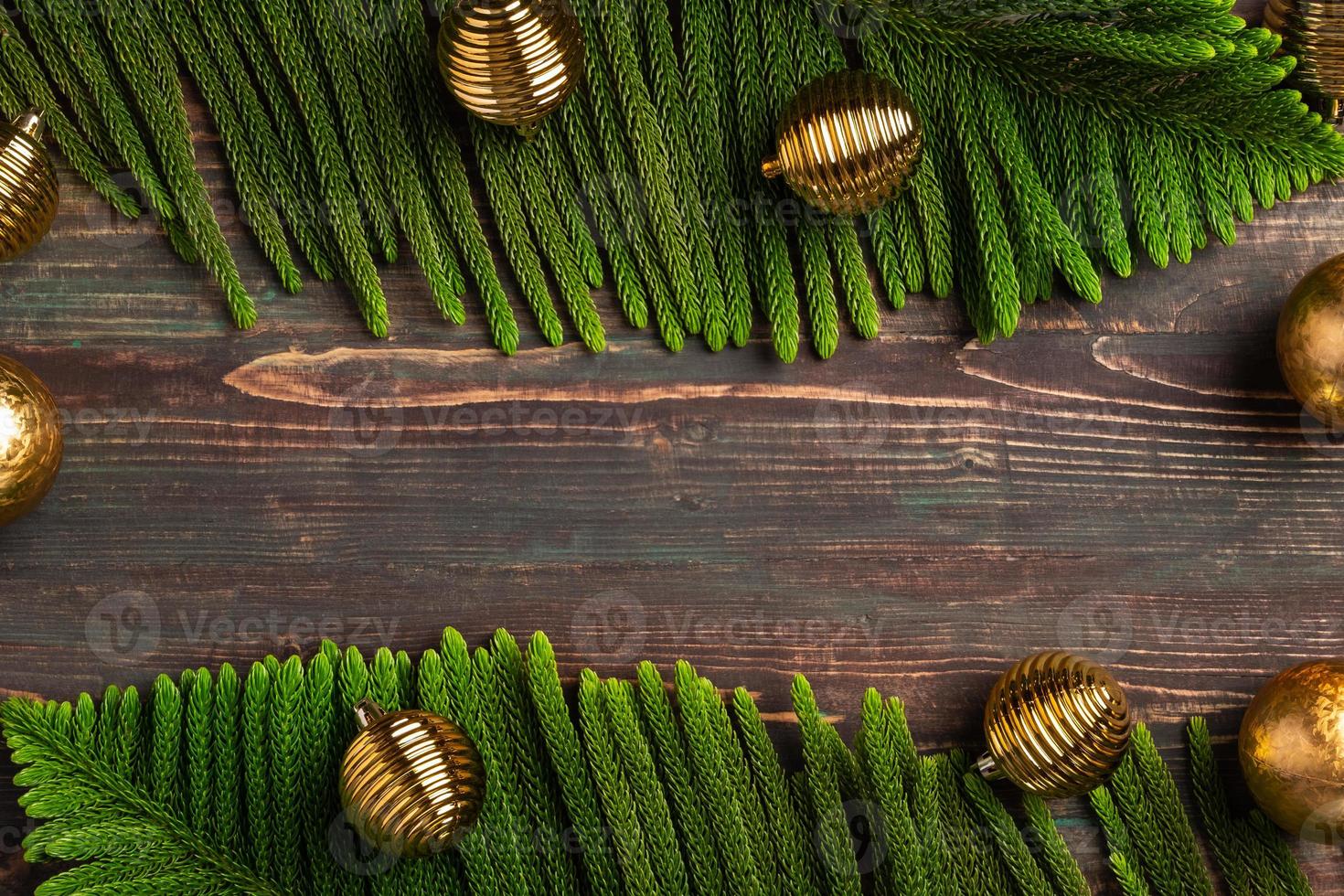 Kerst dennenblad met gouden kerstbal decoratie op houten tafel foto