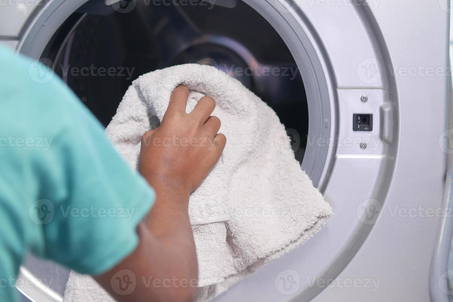 handdoek en doeken in een wasmachine doen. foto