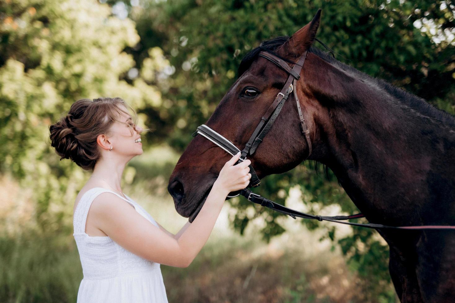 meisje in een witte zomerjurk op een wandeling met bruine paarden foto
