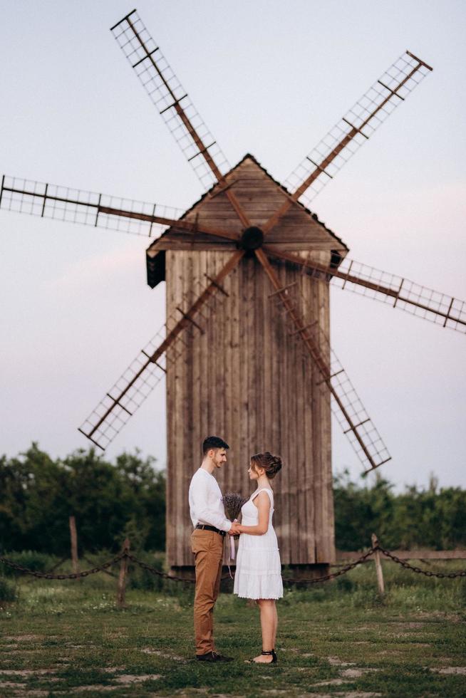 meisje in een witte zomerjurk en een man in een wit overhemd op een wandeling bij zonsondergang met een boeket foto