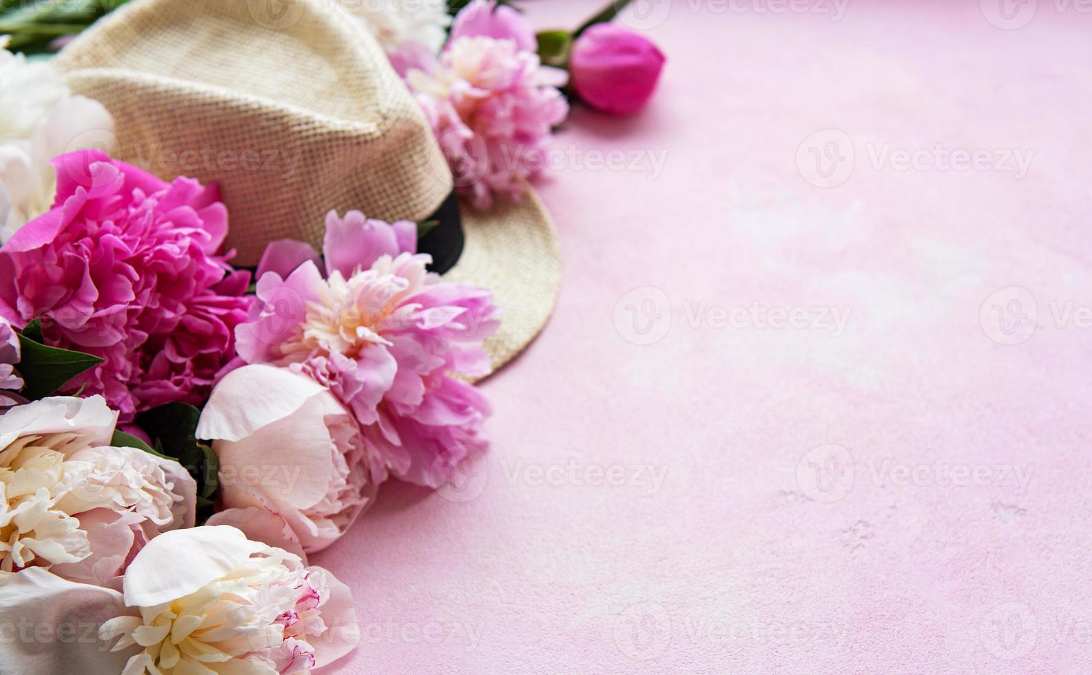 roze pioenrozen en hoed op een roze betonnen ondergrond foto