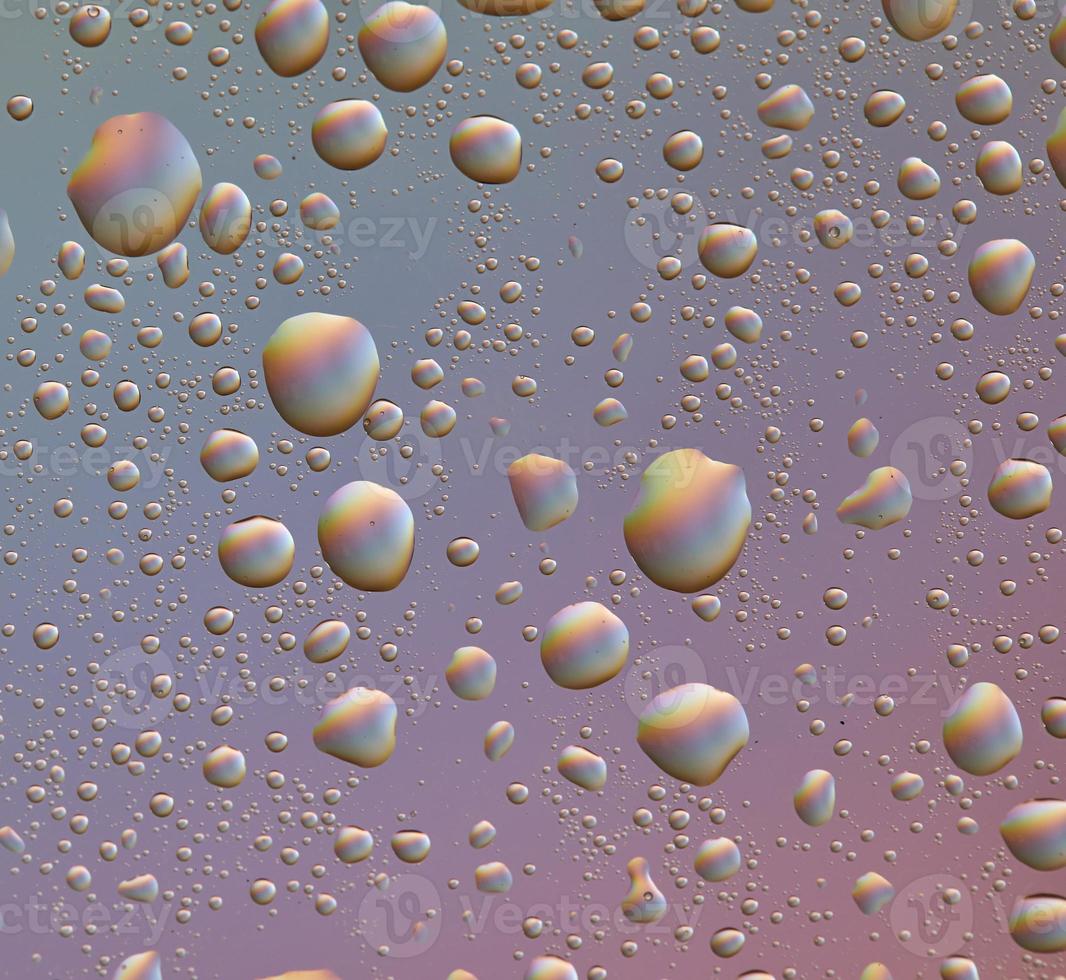druppels op glas van verschillende maten en kleuren op een gekleurde achtergrond, textuur foto
