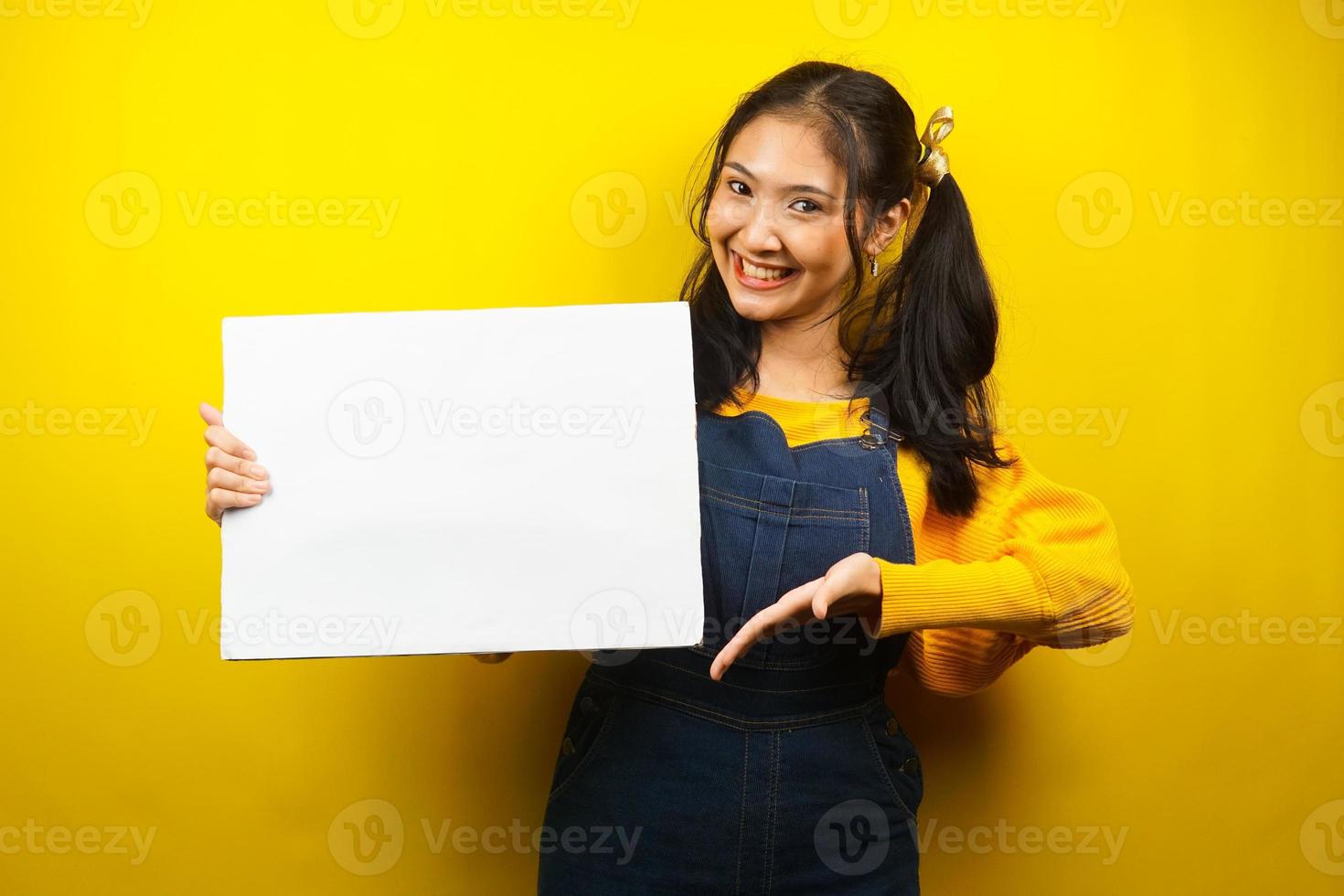 mooie en schattige jonge vrouw vrolijk met lege lege banner, plakkaat, wit bord, leeg bord, wit reclamebord, iets presenteren in kopieerruimte, promotie foto