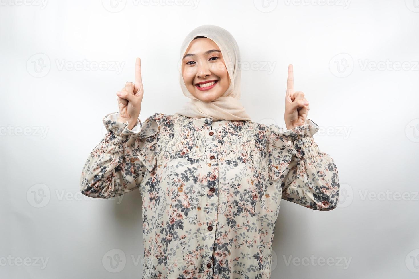 mooie jonge aziatische moslimvrouw die zelfverzekerd, enthousiast en vrolijk glimlacht met handen die omhoog wijzen en iets presenteren, kijkend naar camera geïsoleerd op een witte achtergrond, reclameconcept foto