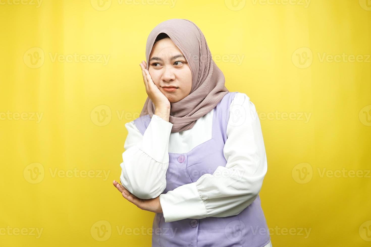 Mooie Aziatische jonge moslimvrouw denken, op zoek naar ideeën, op zoek naar oplossingen voor problemen, met handen met wangen, geïsoleerd op gele achtergrond foto