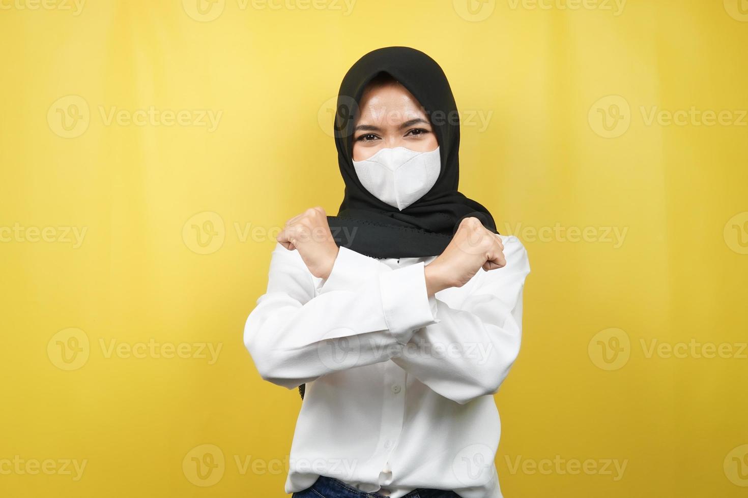moslimvrouw met wit masker, met gebalde vuist, vuist ponsen, corona virus voorkomen, geest om te winnen, geïsoleerd op gele achtergrond foto