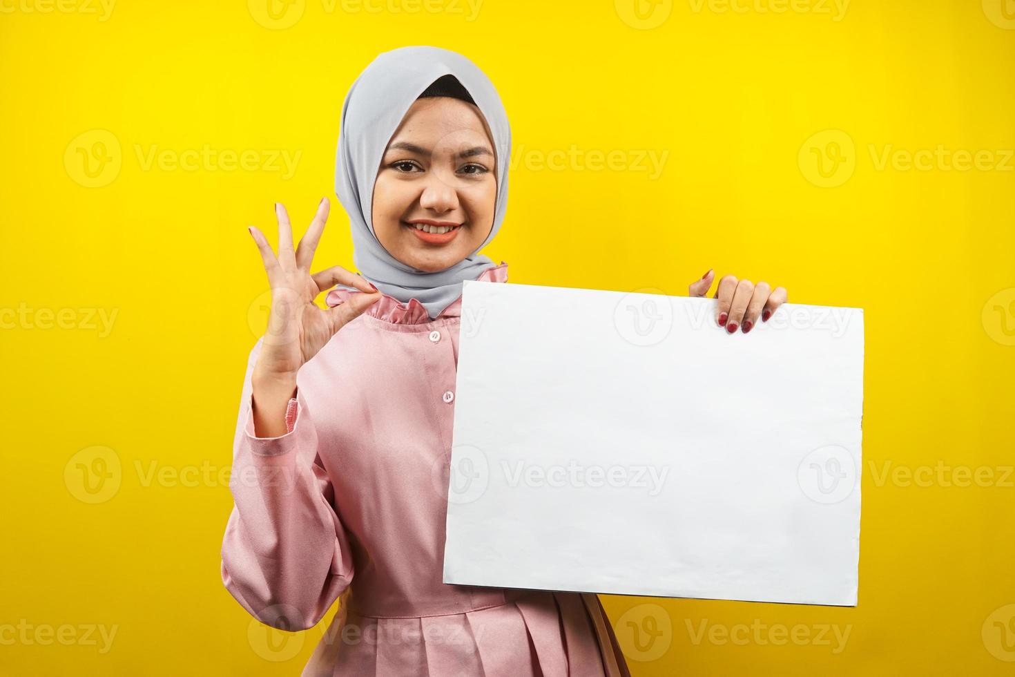 mooie jonge moslimvrouw vrolijk met lege lege banner, plakkaat, wit bord, leeg bord, wit reclamebord, iets presenteren in kopieerruimte, promotie foto