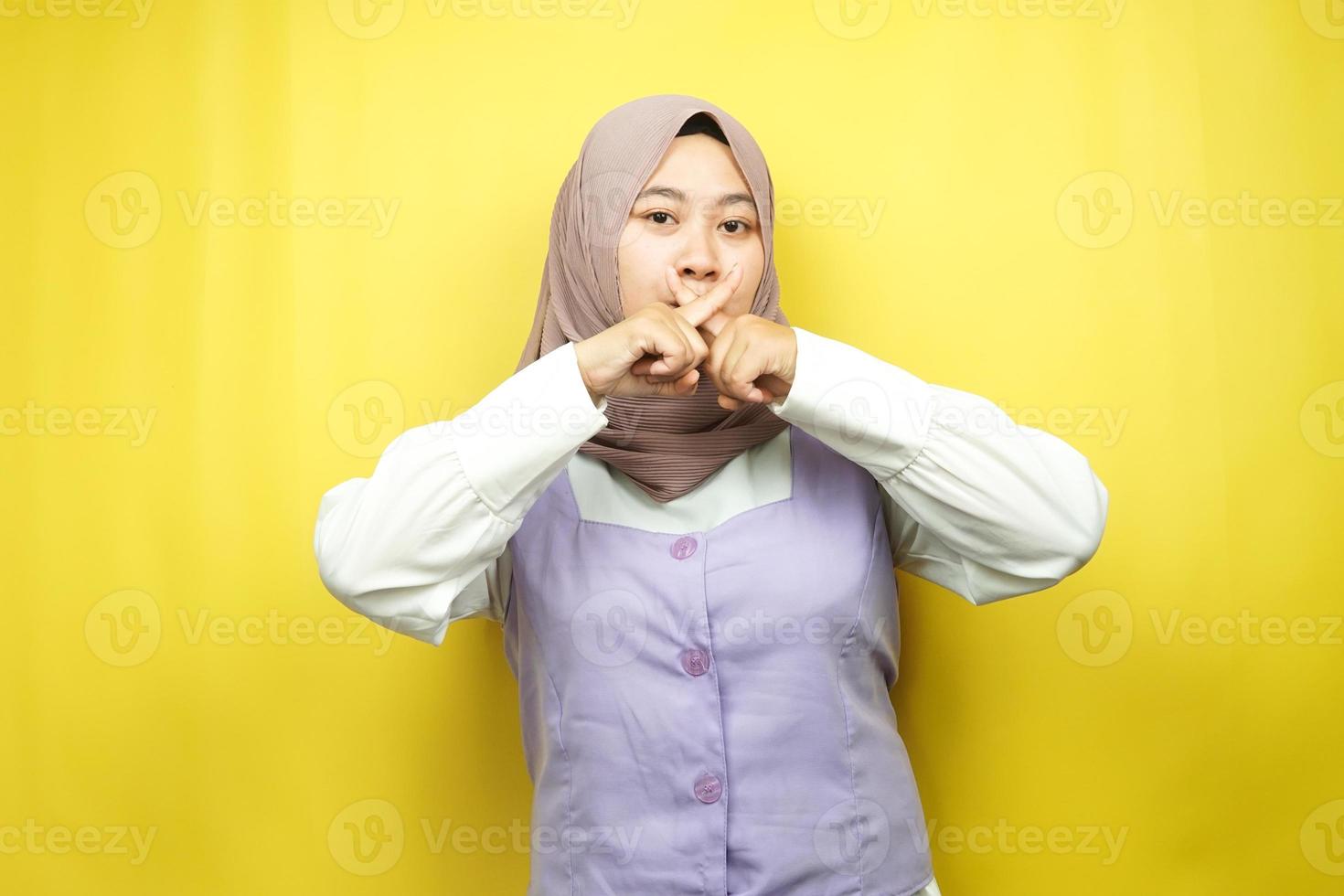 mooie aziatische jonge moslimvrouw met vinger op mond, vertellen stil te zijn, geen lawaai maken, je stem verlagen, niet praten, geïsoleerd op gele achtergrond foto