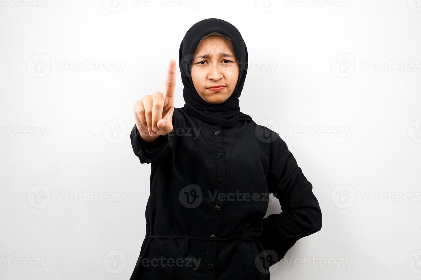 Mooie assertieve Aziatische jonge moslimvrouw, met nummer één teken hand, waarschuwingsbord hand naar camera, geïsoleerd op een witte achtergrond foto