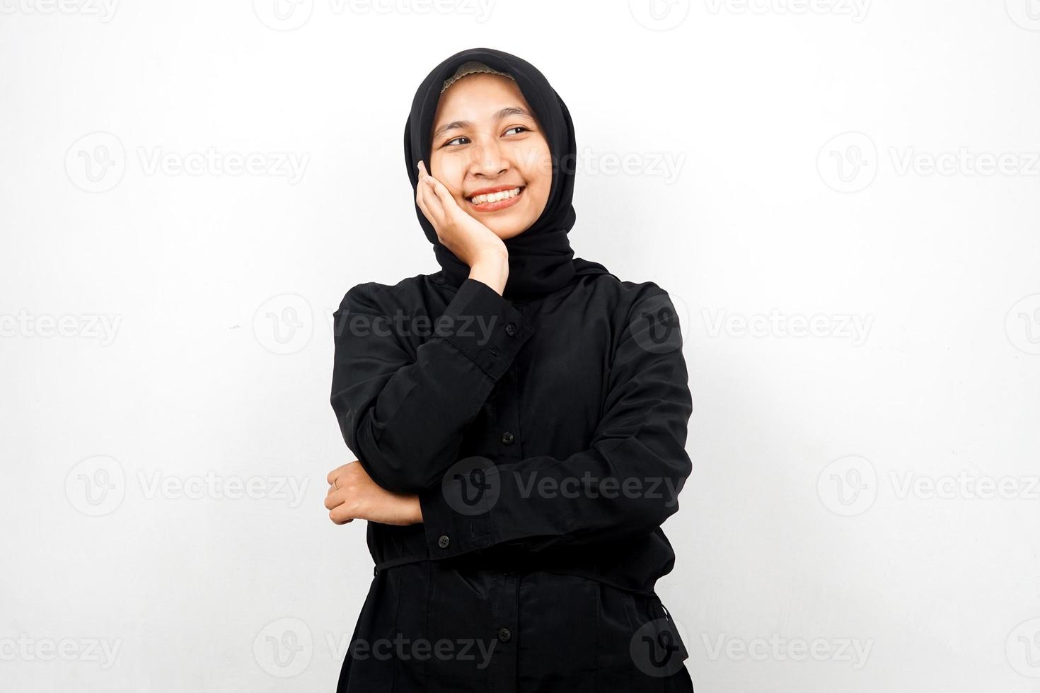 Mooie en vrolijke jonge Aziatische moslimvrouw, kijkend naar lege ruimte, iets presenteren, geïsoleerd op een witte achtergrond foto