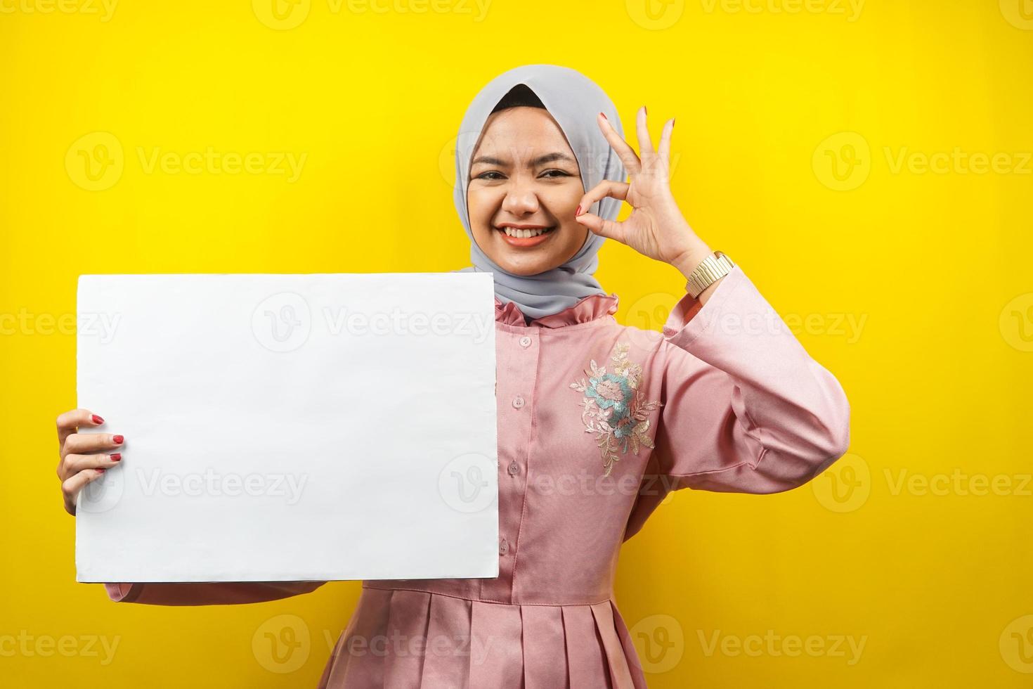 mooie jonge moslimvrouw vrolijk met lege lege banner, plakkaat, wit bord, leeg bord, wit reclamebord, iets presenteren in kopieerruimte, promotie foto