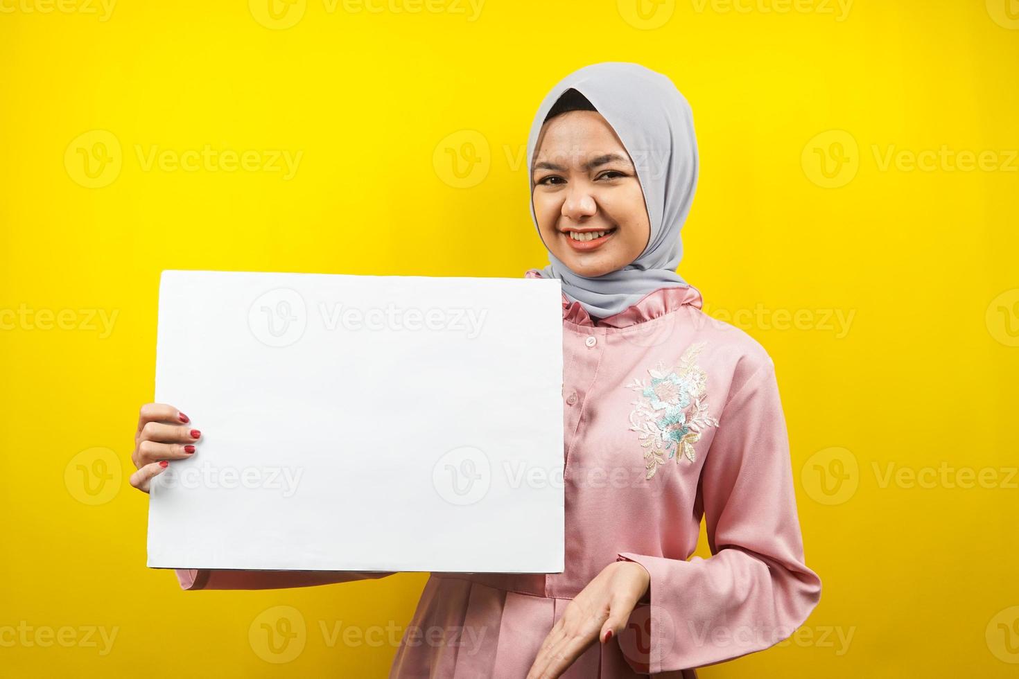 mooie jonge moslimvrouw vrolijk met lege lege banner, plakkaat, wit bord, leeg bord, wit reclamebord, iets presenteren in kopieerruimte, promotie foto