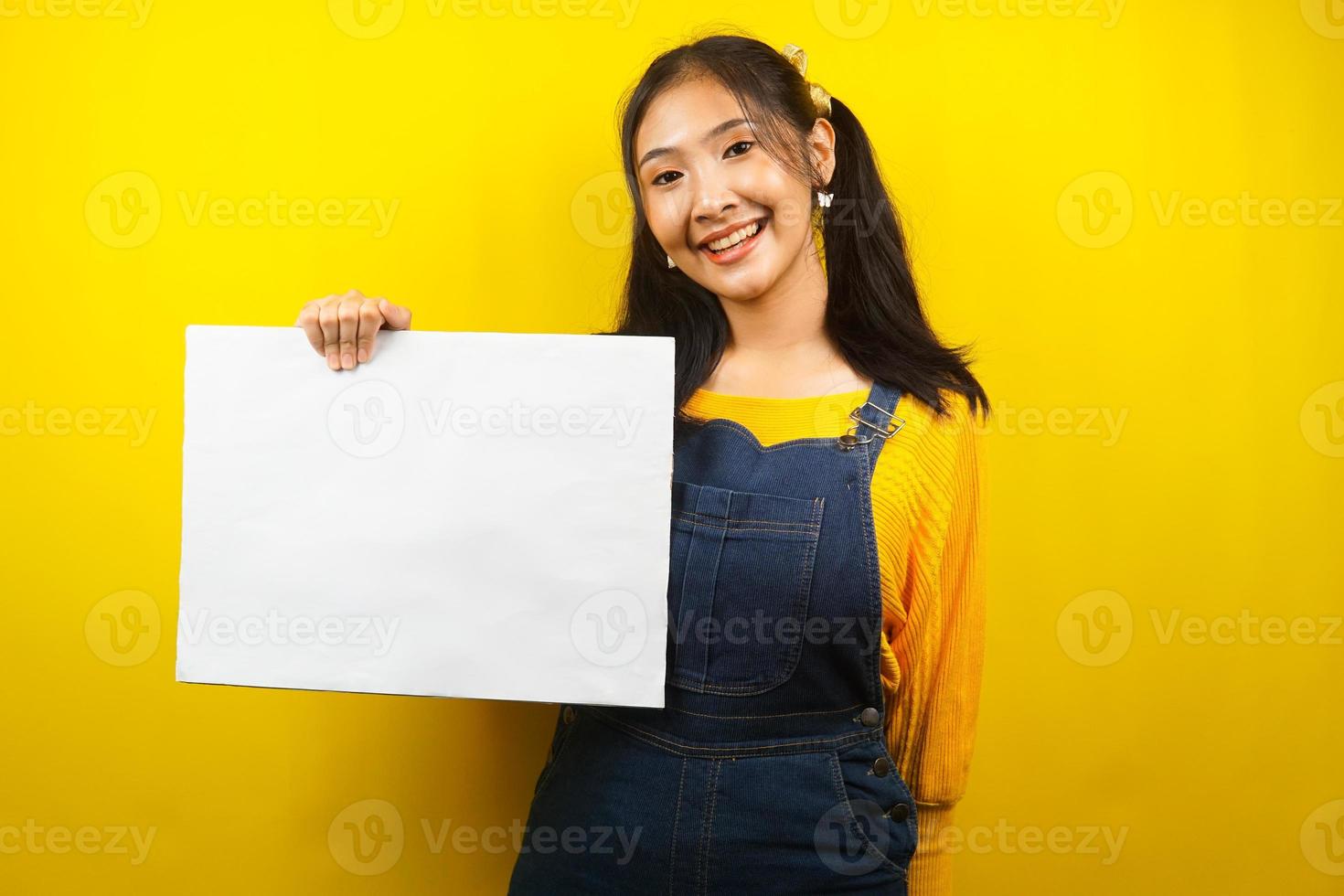 mooie en schattige jonge vrouw vrolijk met lege lege banner, plakkaat, wit bord, leeg bord, wit reclamebord, iets presenteren in kopieerruimte, promotie foto