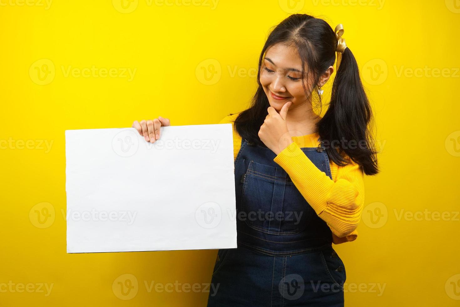 mooie en schattige jonge vrouw vrolijk met lege lege banner, plakkaat, wit bord, leeg bord, wit reclamebord, iets presenteren in kopieerruimte, promotie foto