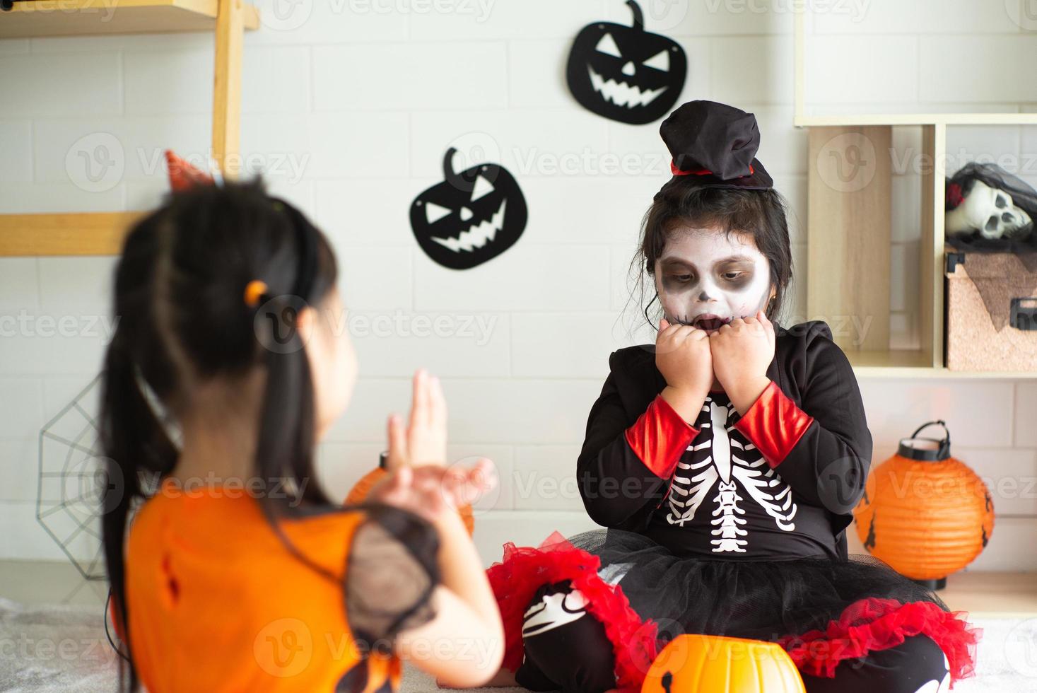 portret van twee zussen in halloween-kostuum die zich gedragen als een spookbeangstigende uitdrukking voor elkaar op halloween-festival foto