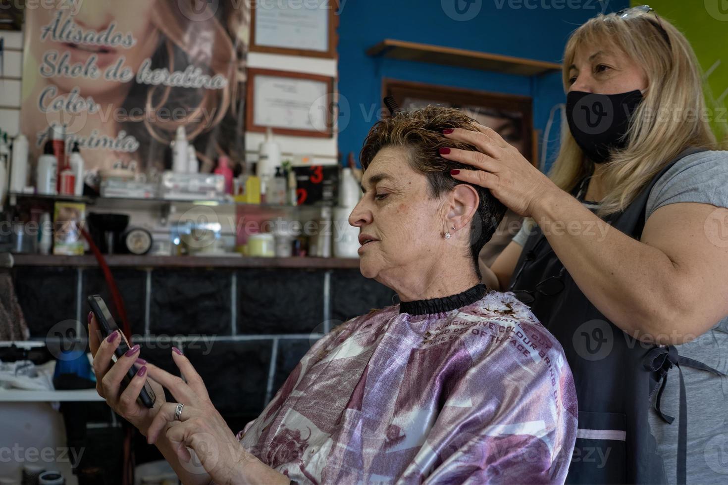 latijnse kapsalon. cliënt die haar mobiele telefoon controleert. foto