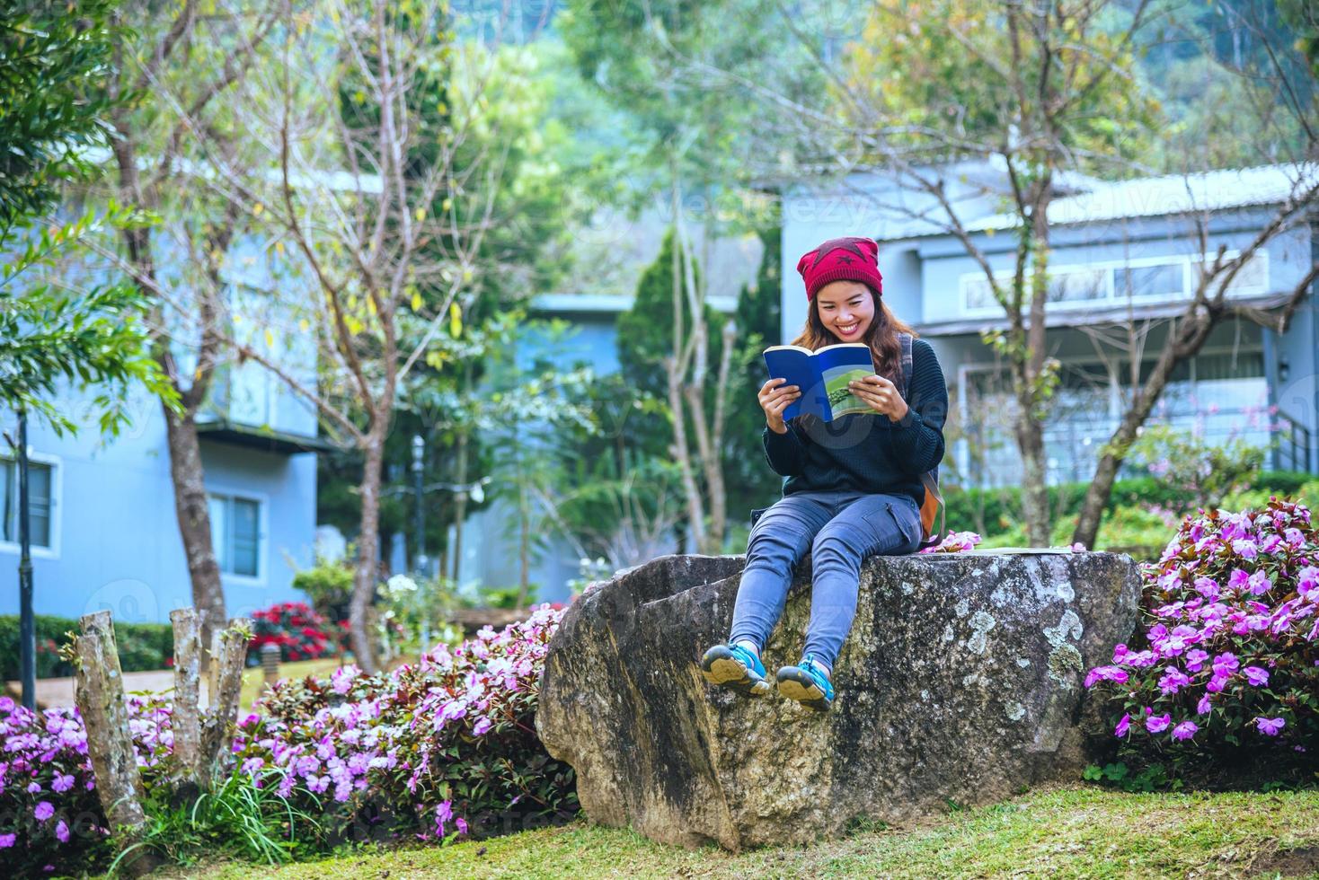 vrouw reizen natuur in de bloementuin. ontspan zittend op rotsen en lees boeken midden in de natuur bij doi inthanon. foto