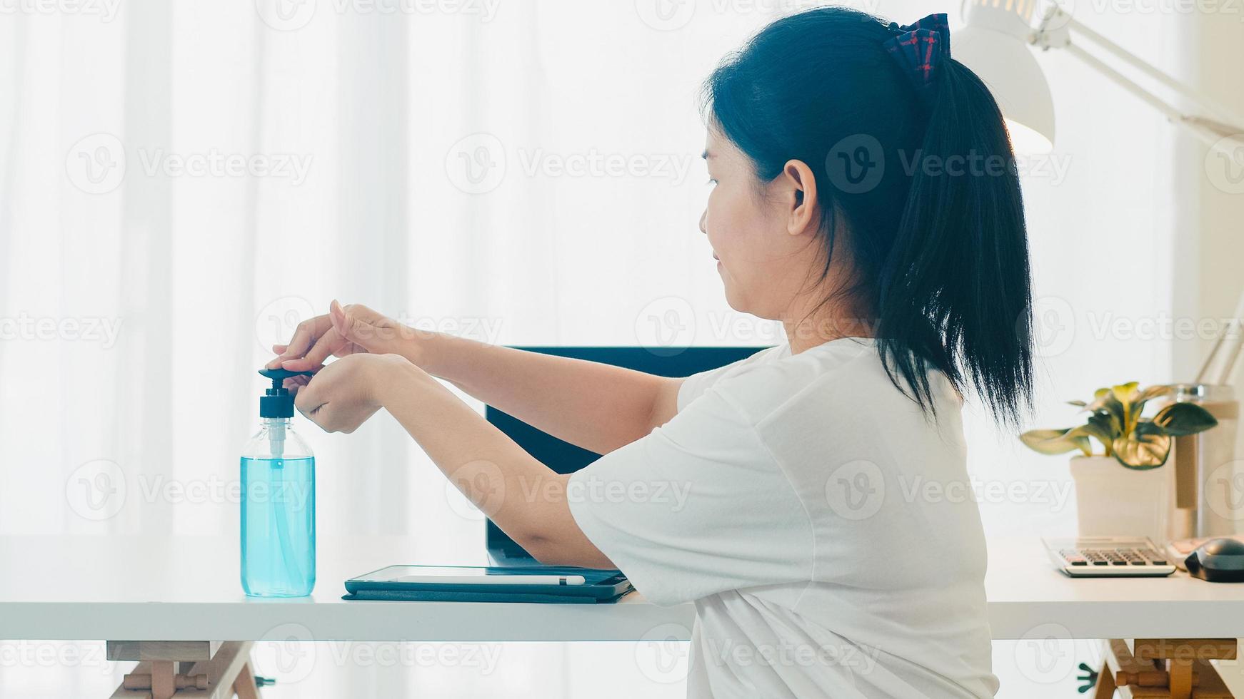 aziatische vrouw die alcoholgel handdesinfecterend middel gebruikt, was de hand voor het openen van de tablet om het coronavirus te beschermen. vrouw duwt alcohol om schoon te maken voor hygiëne wanneer social distancing thuis blijft en zelfquarantainetijd foto