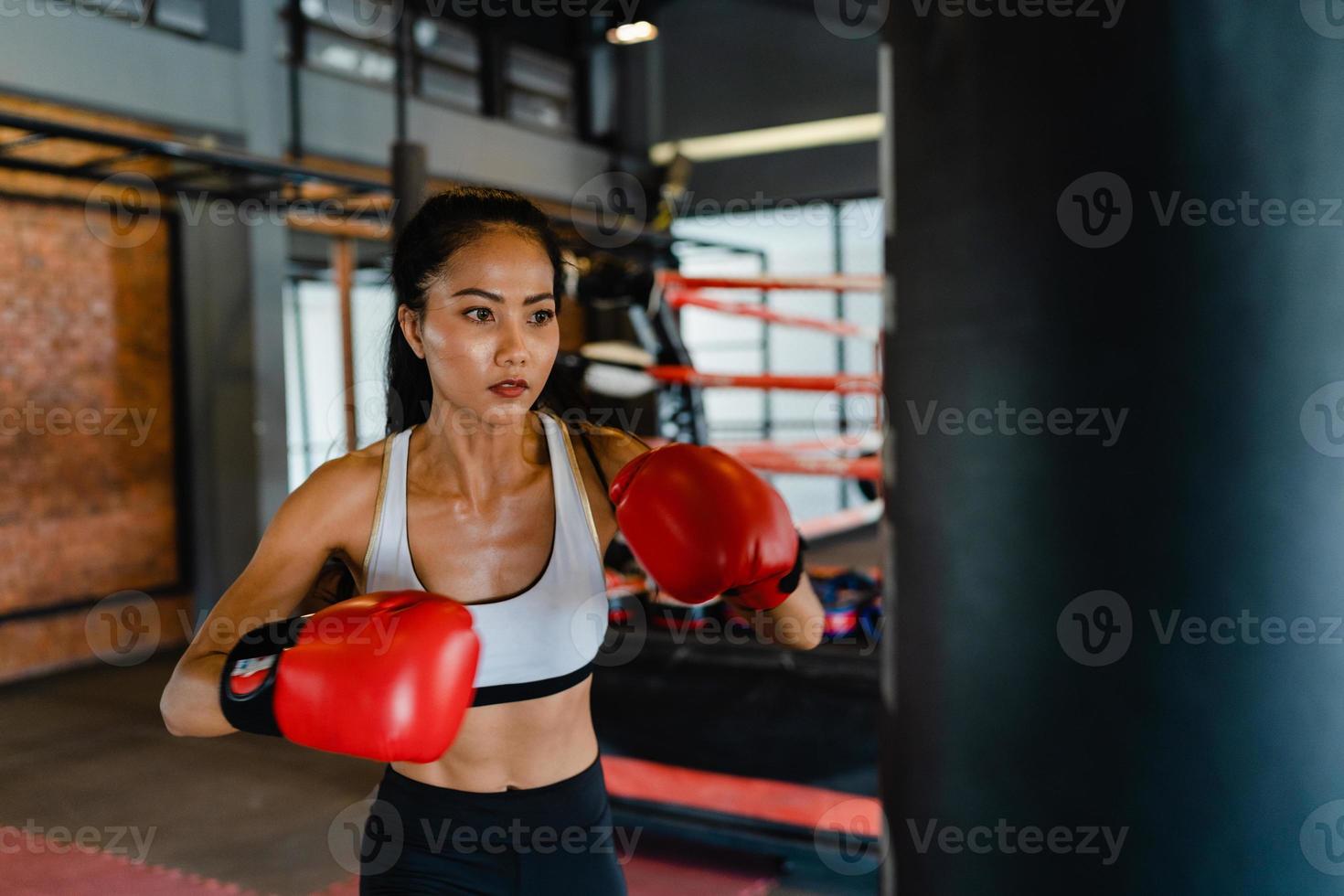 jonge azië dame kickboksen oefening training bokszak stoere vrouwelijke vechter praktijk boksen in gym fitness klasse. sportvrouw recreatieve activiteit, functionele training, gezonde levensstijl concept. foto