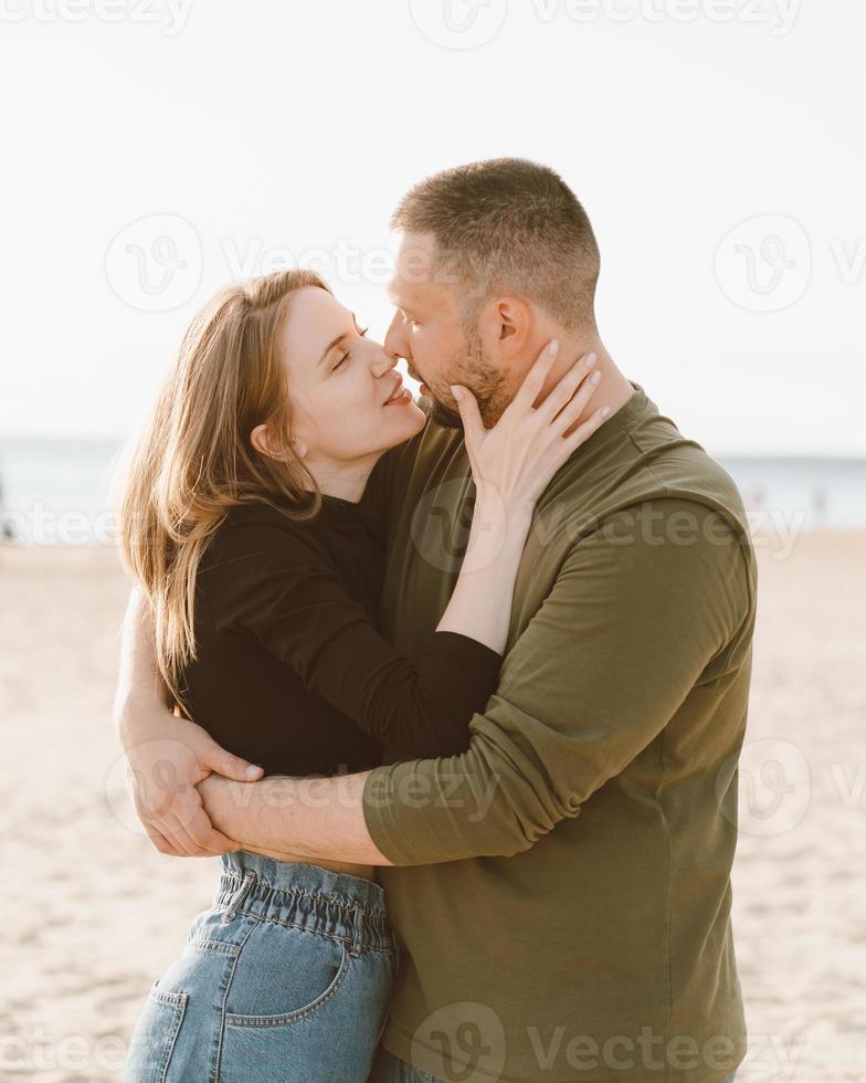 jong volwassen paar staande op het strand en op zoek naar elkaar. foto