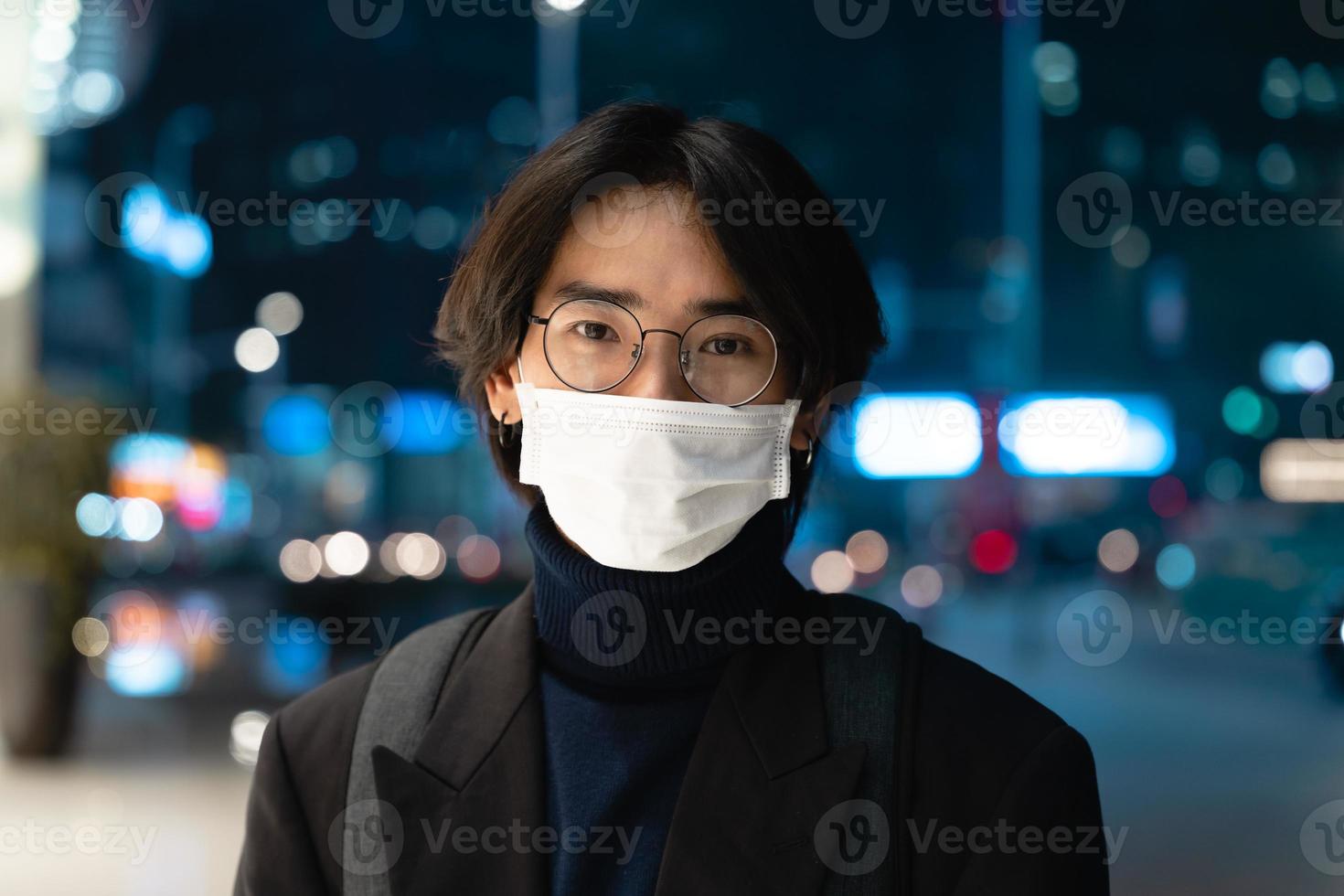 portret van een Aziatische zakenman die een masker draagt, 's nachts op straat foto