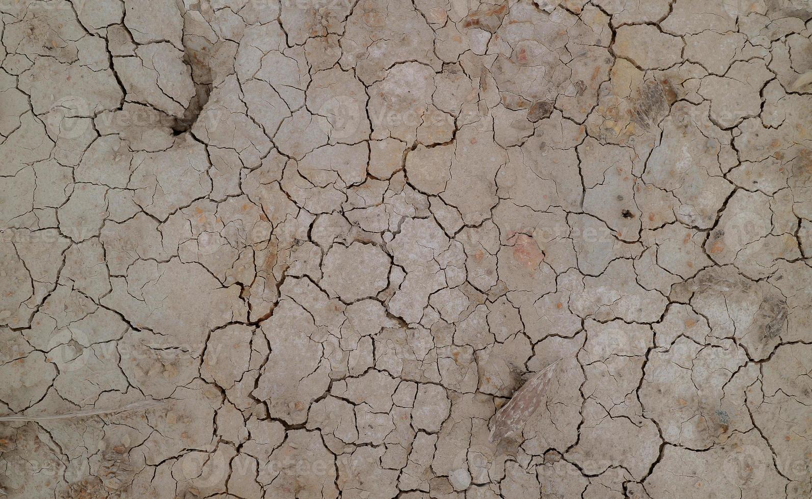 grond gebarsten door droogte. droge seizoen zorgt ervoor dat de grond uitdroogt en barst foto