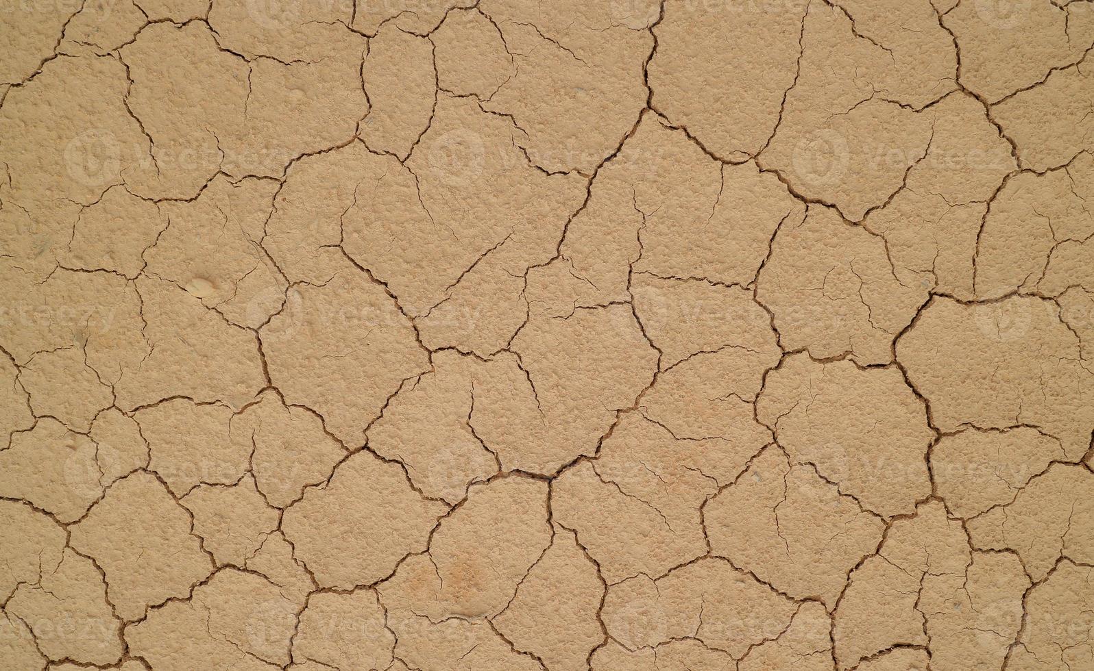 grond gebarsten door droogte. droge seizoen zorgt ervoor dat de grond uitdroogt en barst foto