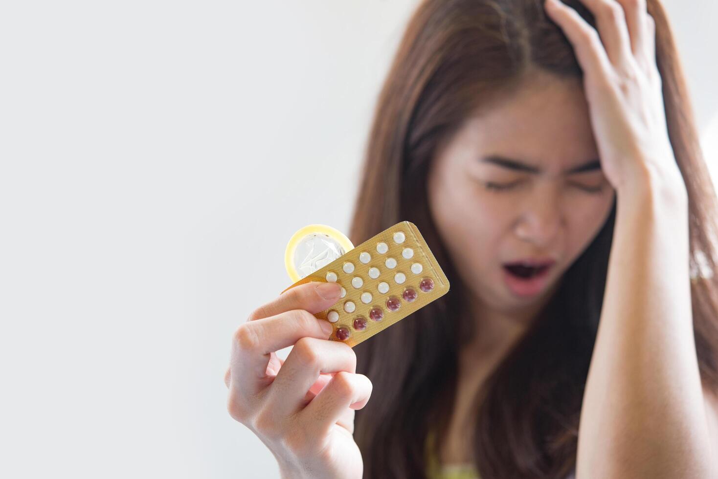 jonge vrouw met condoom en anticonceptiepillen voorkomt zwangerschap foto