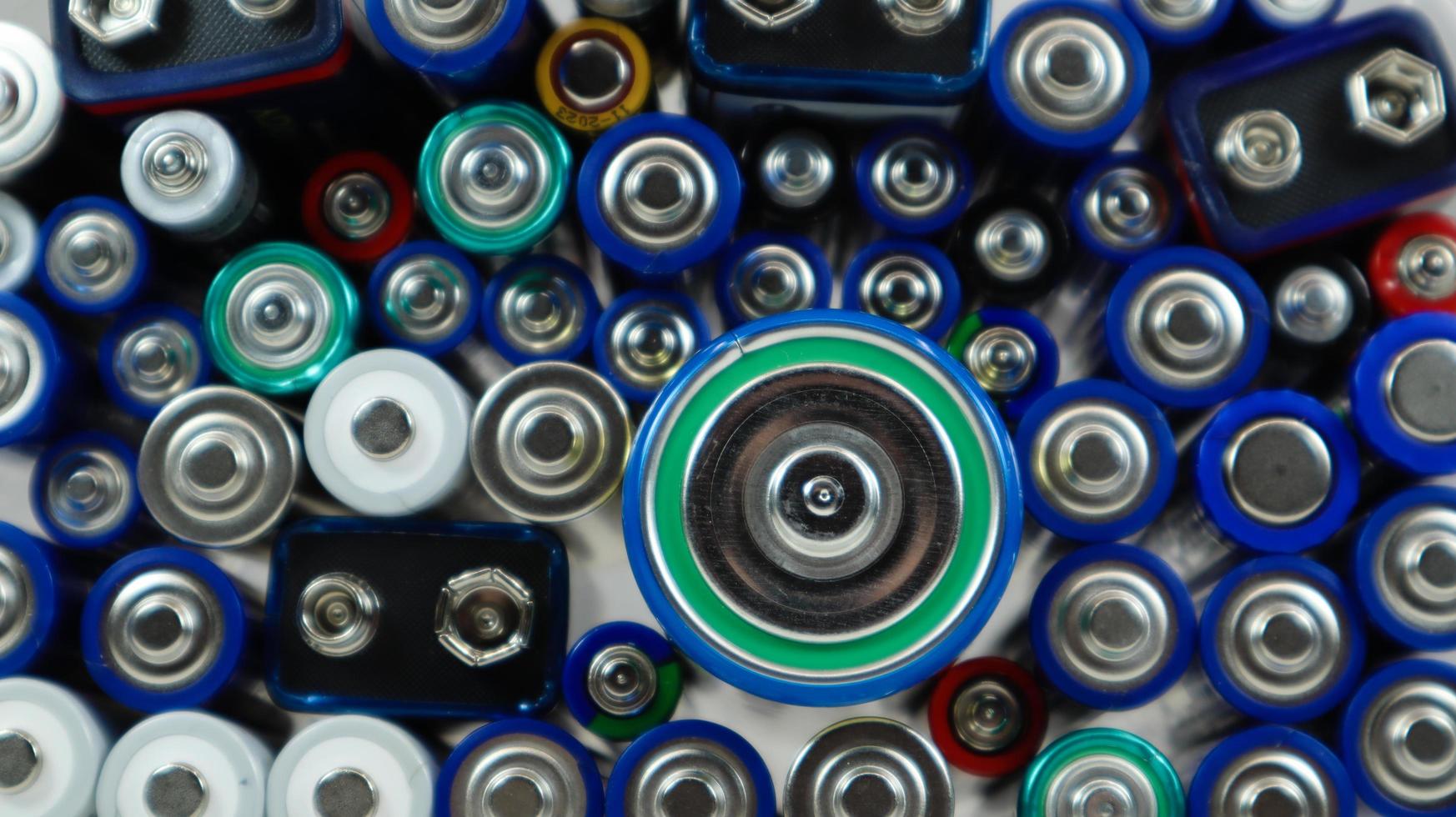 veel gebruikte huishoudelijke alkalinebatterijen type aa, aaa, pp3, d, c, ingezameld voor recycling. recycling en ecologische problemen. bovenaanzicht van een achtergrond van gebruikte batterijen van verschillende soorten en maten. foto