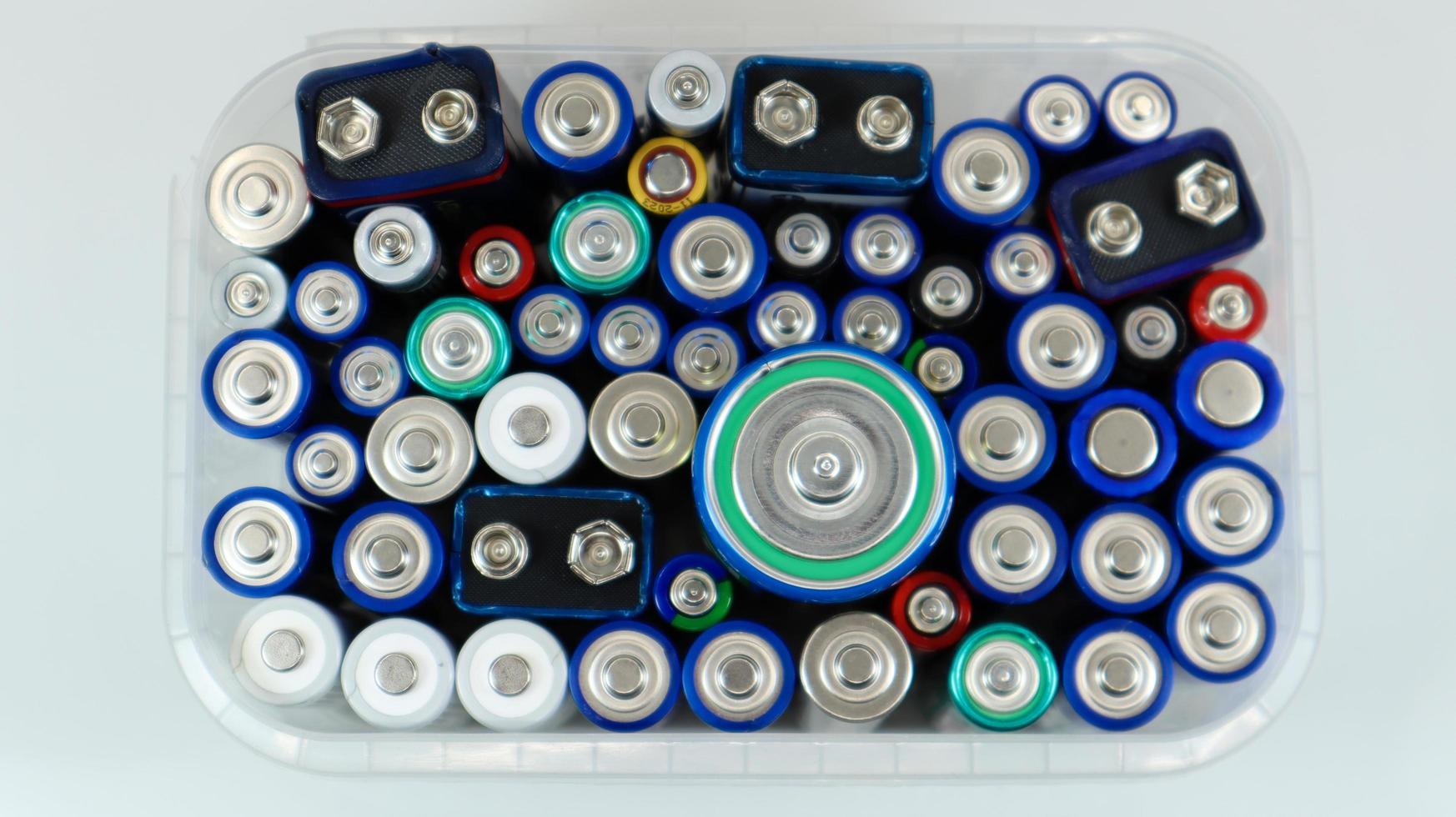 doorzichtige plastic doos vol gebruikte huishoudelijke AA-alkaline- en lithium-ionbatterijen verzameld voor recycling in speciale afvalbakken. recycling en ecologische problemen. uitzicht van boven foto
