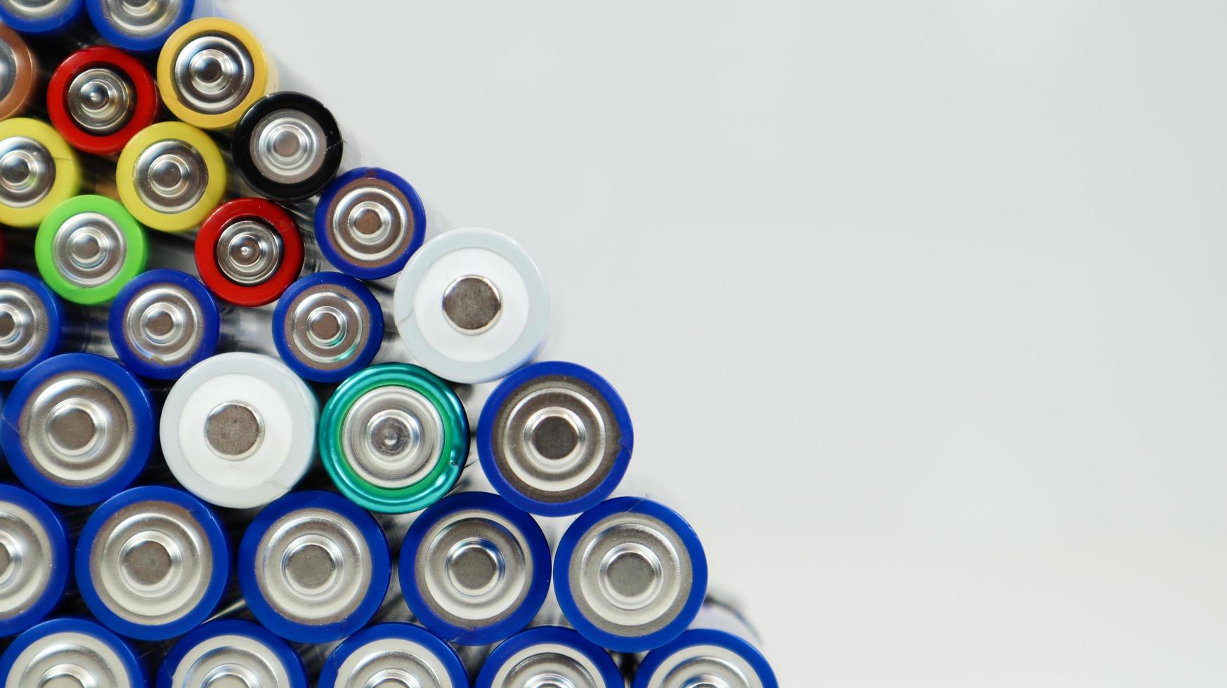 veel AA- en aaa-alkalinebatterijen op een witte achtergrond. ecologisch recyclingconcept. de polen van de wegwerpbatterijen liggen dicht bij elkaar en vormen een prachtig decor. energiebron. foto