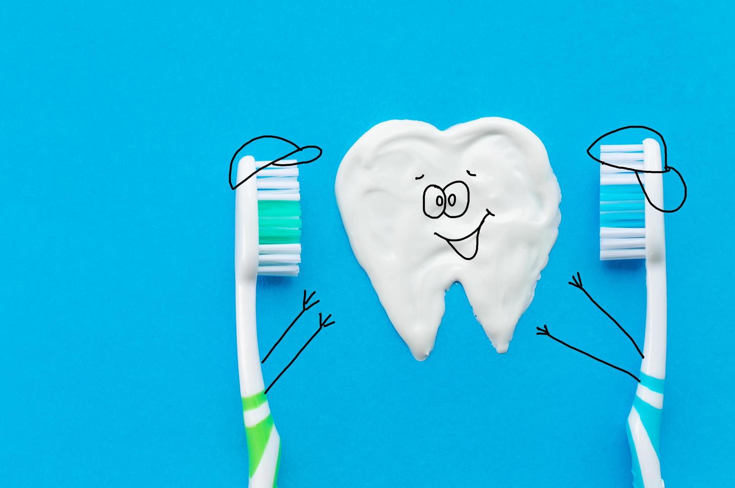 veelkleurige tandenborstels op een blauwe achtergrond met een tandpatroon getekend met tandpasta in de vorm van stripfiguren. het uitzicht vanaf de top.the concept van tandheelkundige gezondheid. foto