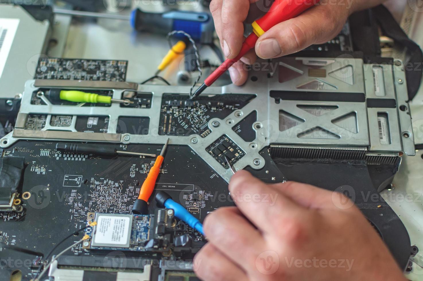 een man repareert een computer, soldeert een bord, repareert elektronica en moderne technologieën foto