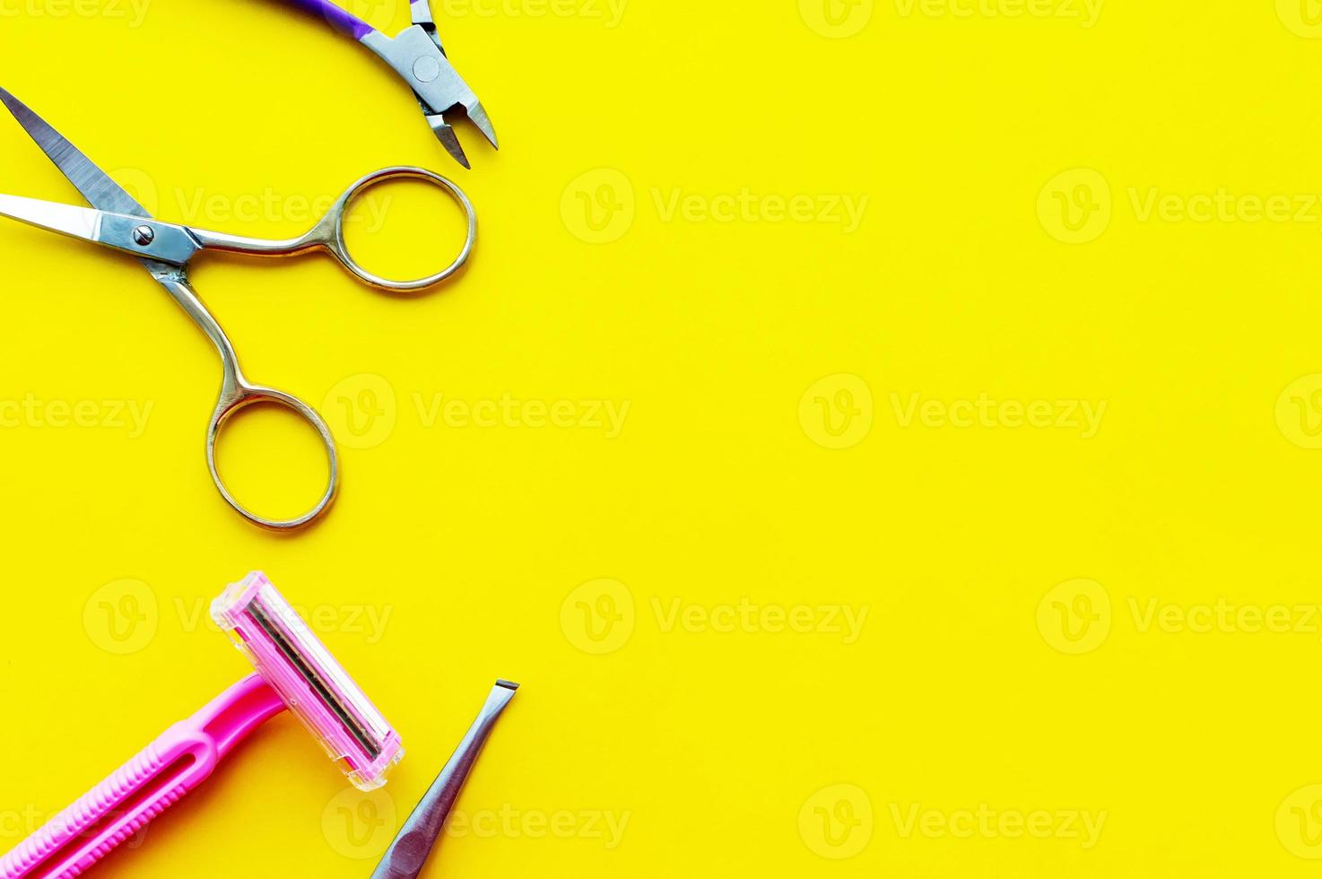 scheermachine, schaar, wenkbrauwtang en nagelknipper op een gele achtergrond met een plek om te schrijven foto