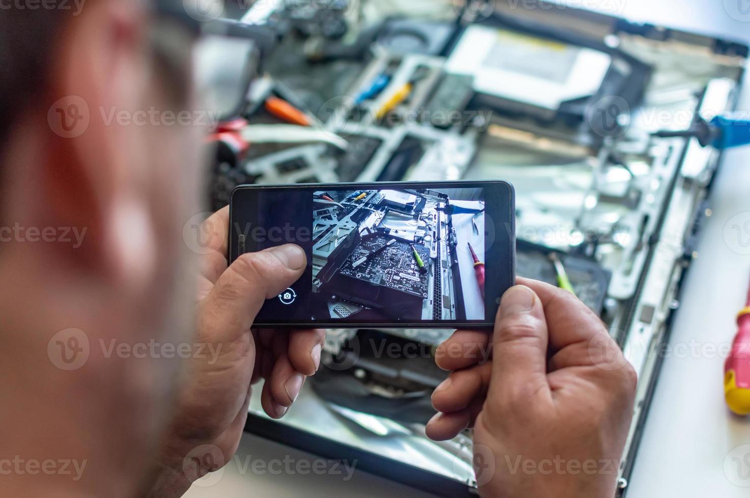 een man repareert een computer, soldeert een bord, repareert elektronica en moderne technologieën foto