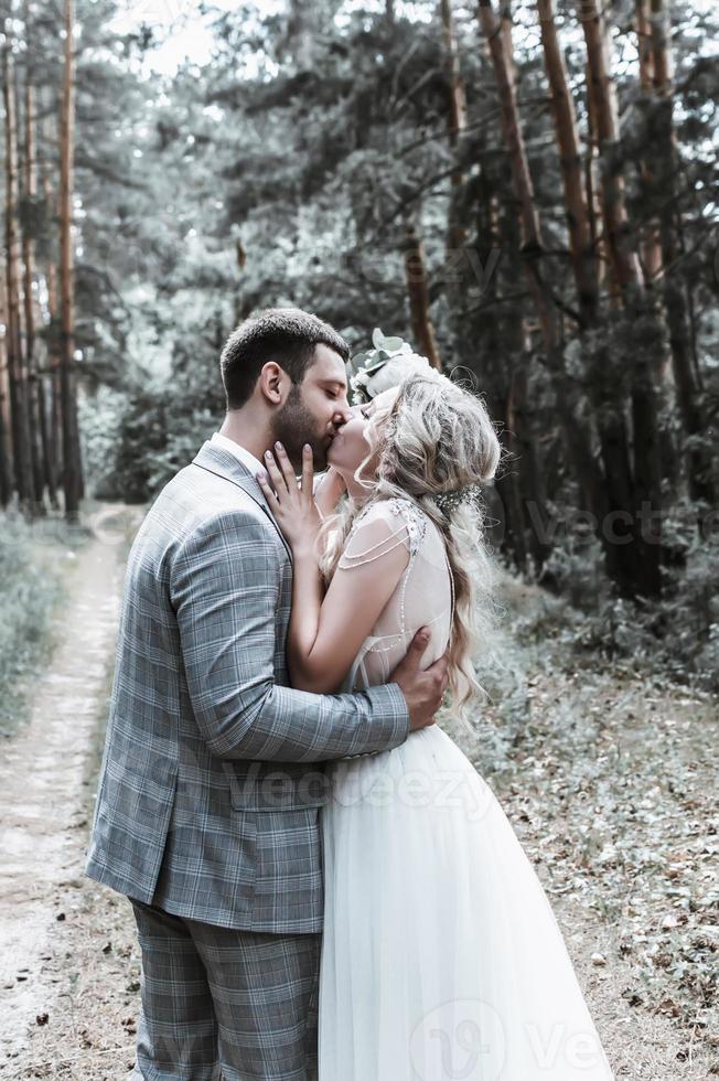 de bruid en bruidegom kussen in het bos tijdens de huwelijksceremonie. selectieve aandacht. film graan. foto