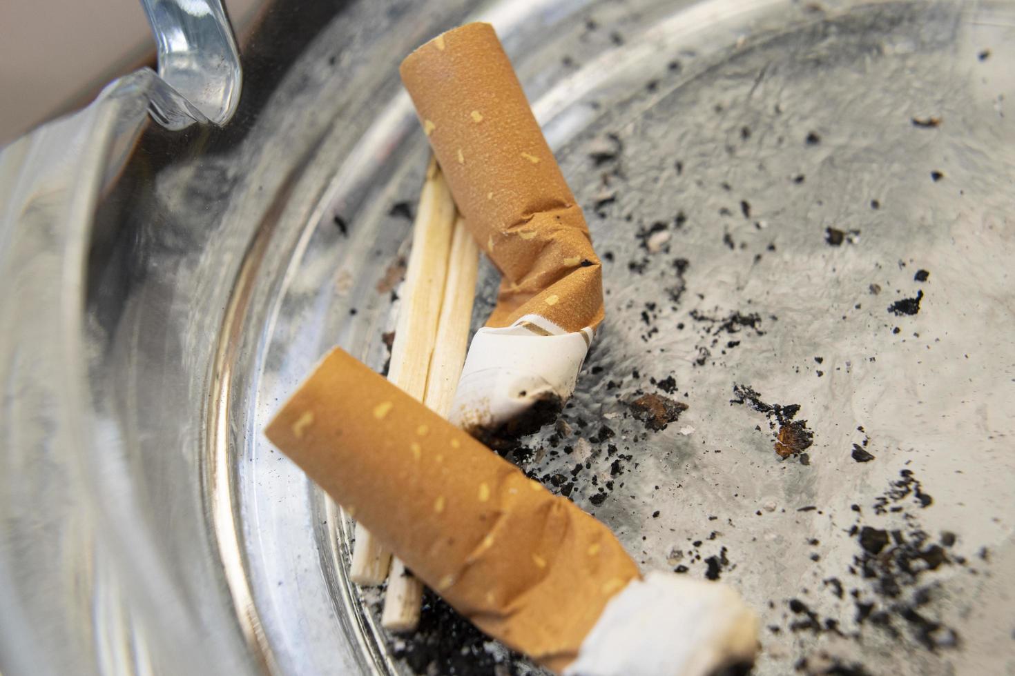 macro close-up op twee gerookte sigarettenpeuken en twee luciferstokjes in een asbak. foto